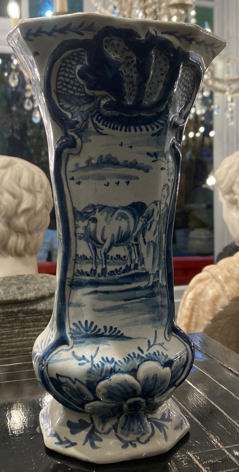 A rare authentic four piece blue and white Dutch delft garniture set with two baluster vases with finial tops and two matching beaker vases. Skilfully hand painted with a countryside landscape scene on one side and a swirled motif on the other. This