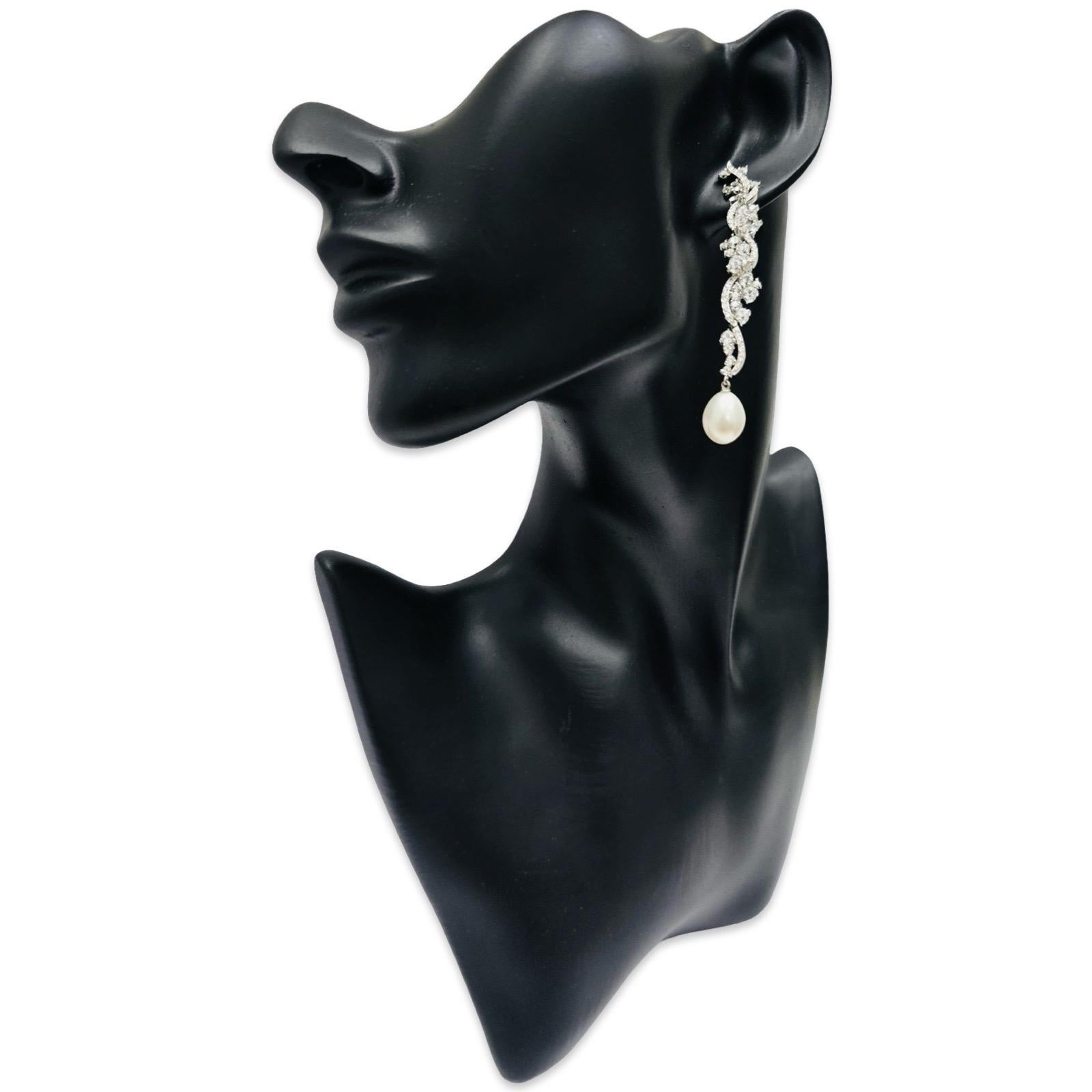 Exceptionnelles boucles d'oreilles pendantes signées Hueb en or blanc 18 carats, ornées de diamants et de perles, mettant en valeur le motif sculptural emblématique de la marque, la vigne. Réalisées en or blanc 18 carats et marquées FR HUEB 750, ces