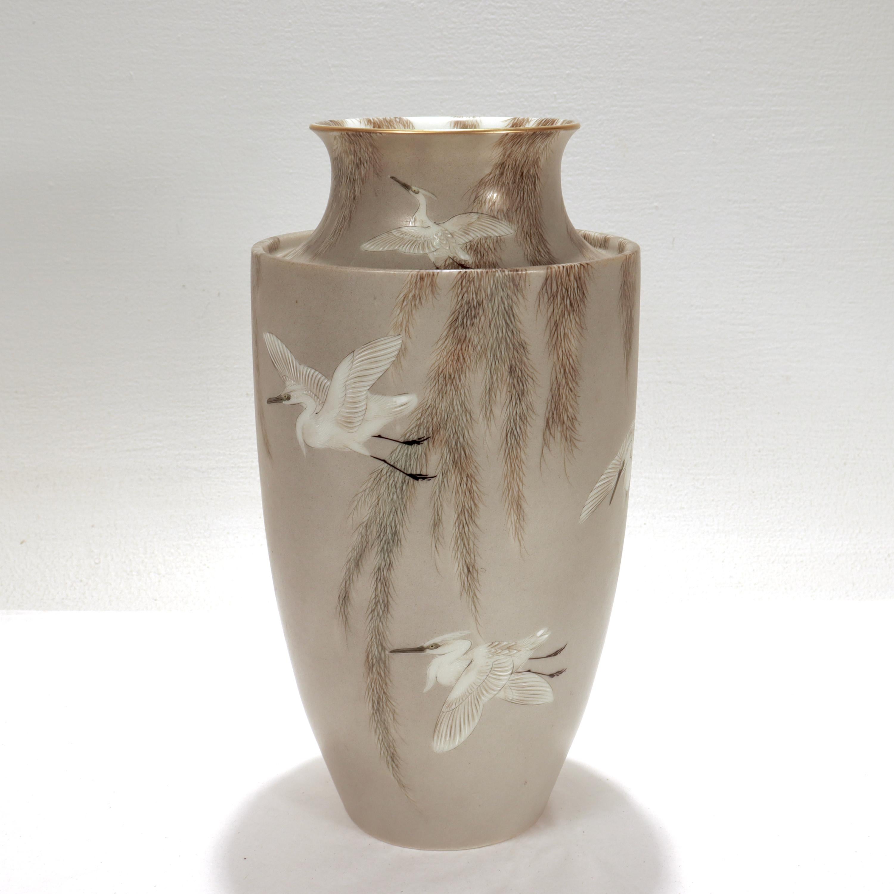 A fine Japanese porcelain vase from the Meiji or Taisho period.

By Imura Hikojiro (?????, b. unknown - d. ca. 1897). 

With a suppressed neck (or everted sidewall), a gilt rim, and tapered sides.

Handpainted with egrets in flight amongst