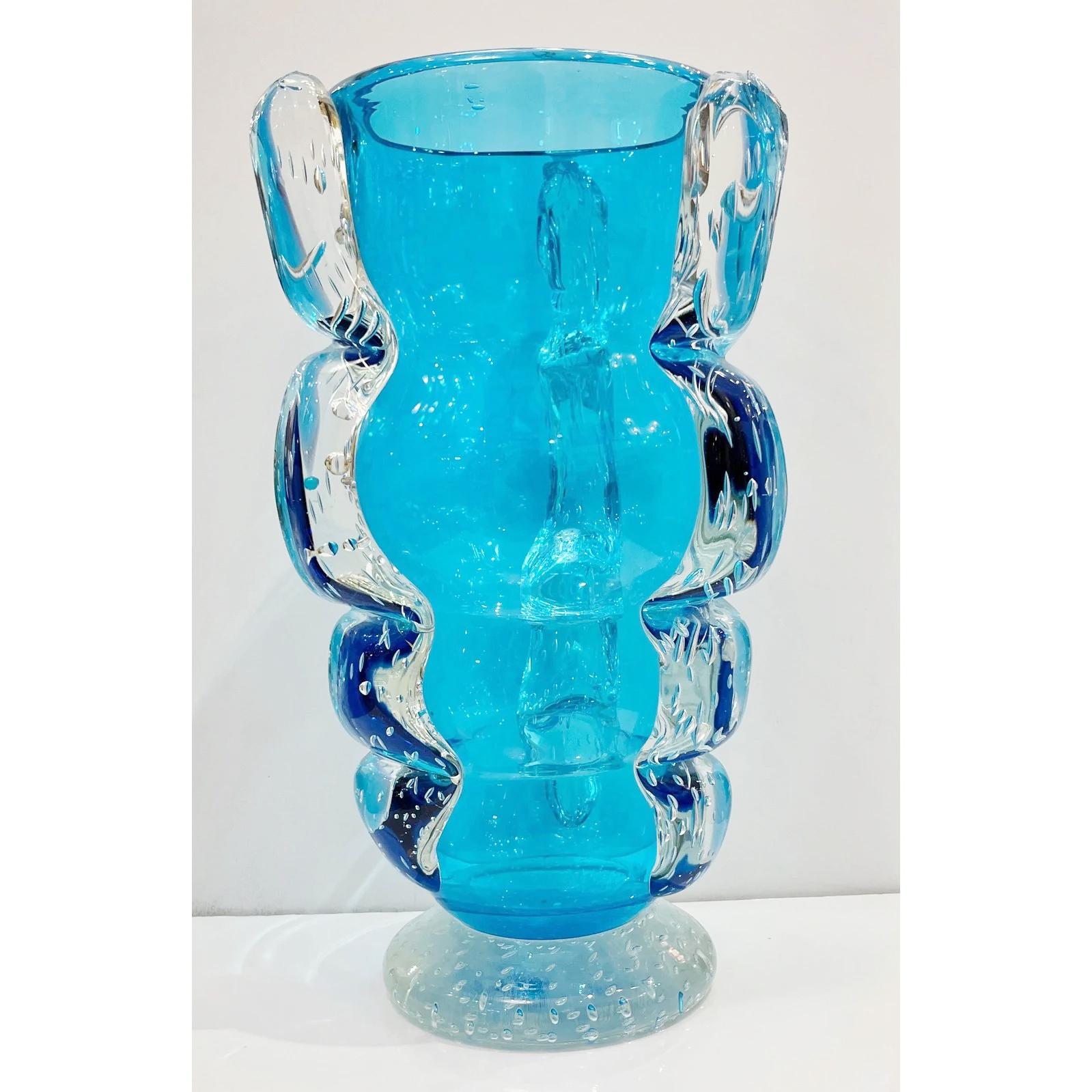 Late 1970s vase in very thick and quality blown Murano glass in an unusual translucent aqua blue color, with a rare wavy form. The body shows a triple decoration of clear glass in relief, worked with bubbles to match the base, that enhances the
