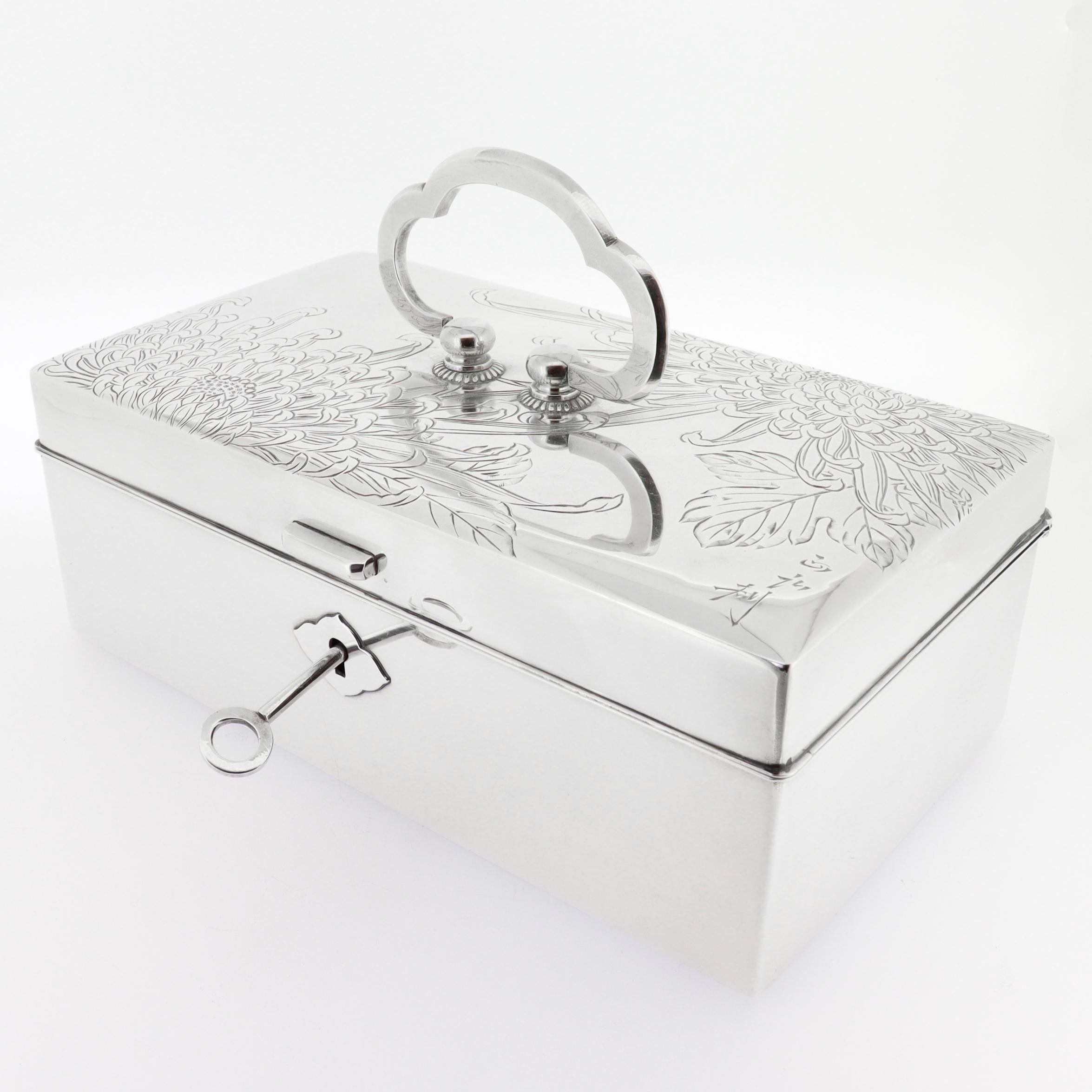 A fine signed Japanese silver jewelry box.

In .950 sterling silver.

With intricate engraved chrysanthemum decoration and a trefoil handle to the lid.

The interior with a lacquered wood and velvet lining to both the lid and body with a matching