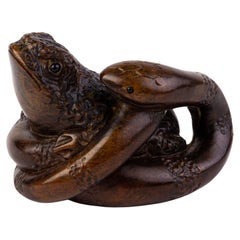 Netsuke japonais signé en bois foncé représentant un serpent piégeant un crapaud