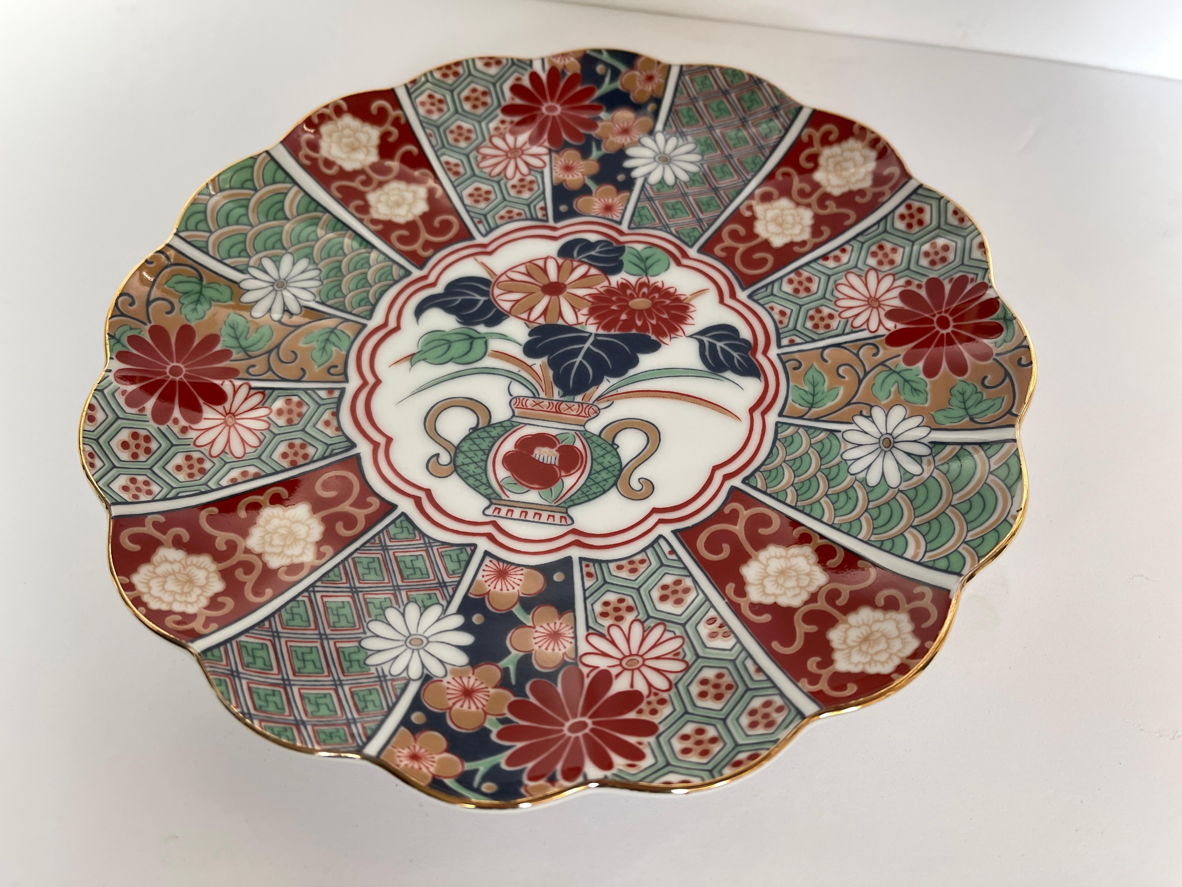Japanese Imari fluted porcelain plate hand decorated with floral design and 
gilt painted rim. Hand signed Japanese signature on bottom.