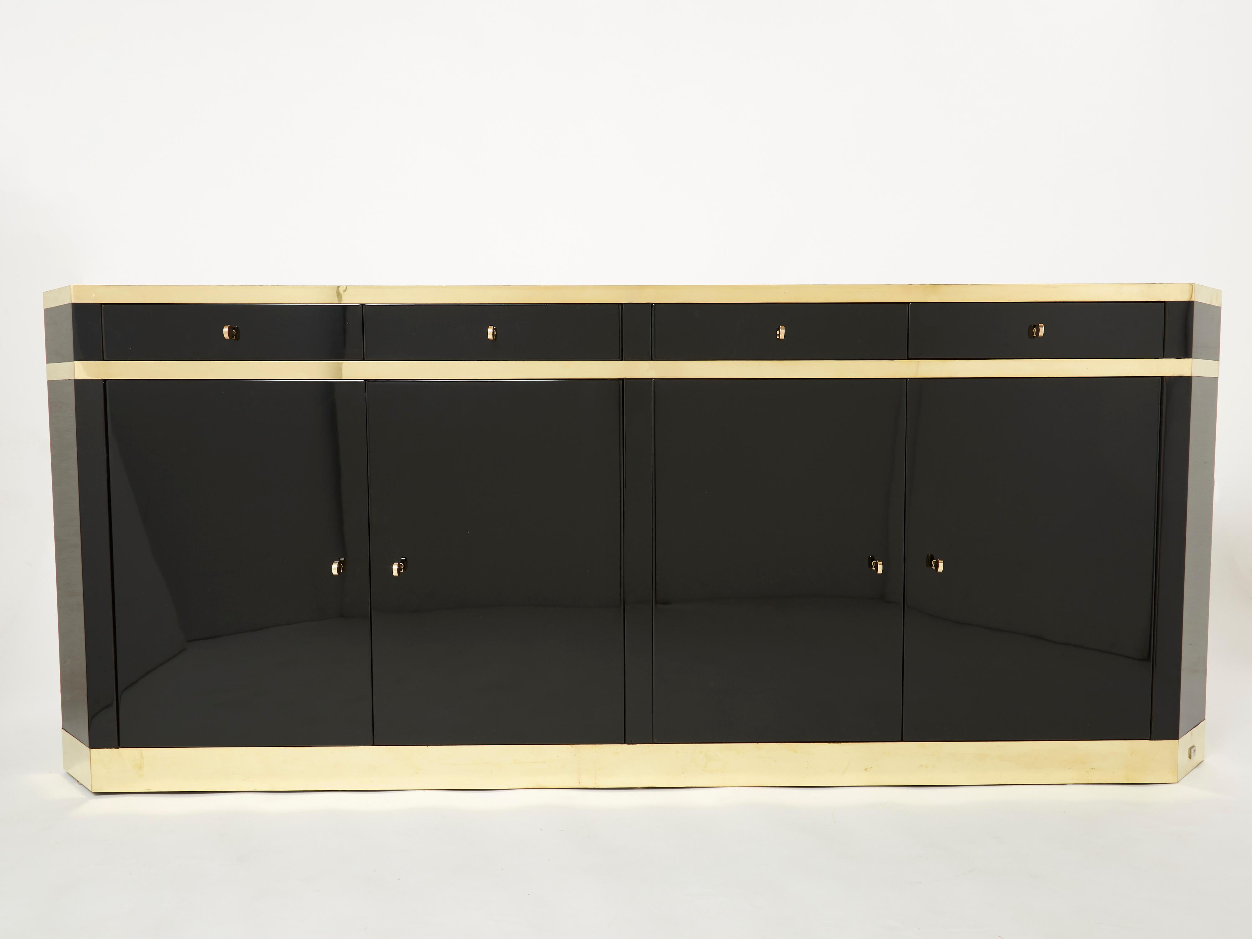 A timeless vintage piece, this mid-century sideboard feels imposing and glamourous, with thick, straight lines of brass adorning its exterior of reflective black lacquer. Glossy black lacquer, paired with bright brass accents and keys, feels crisp