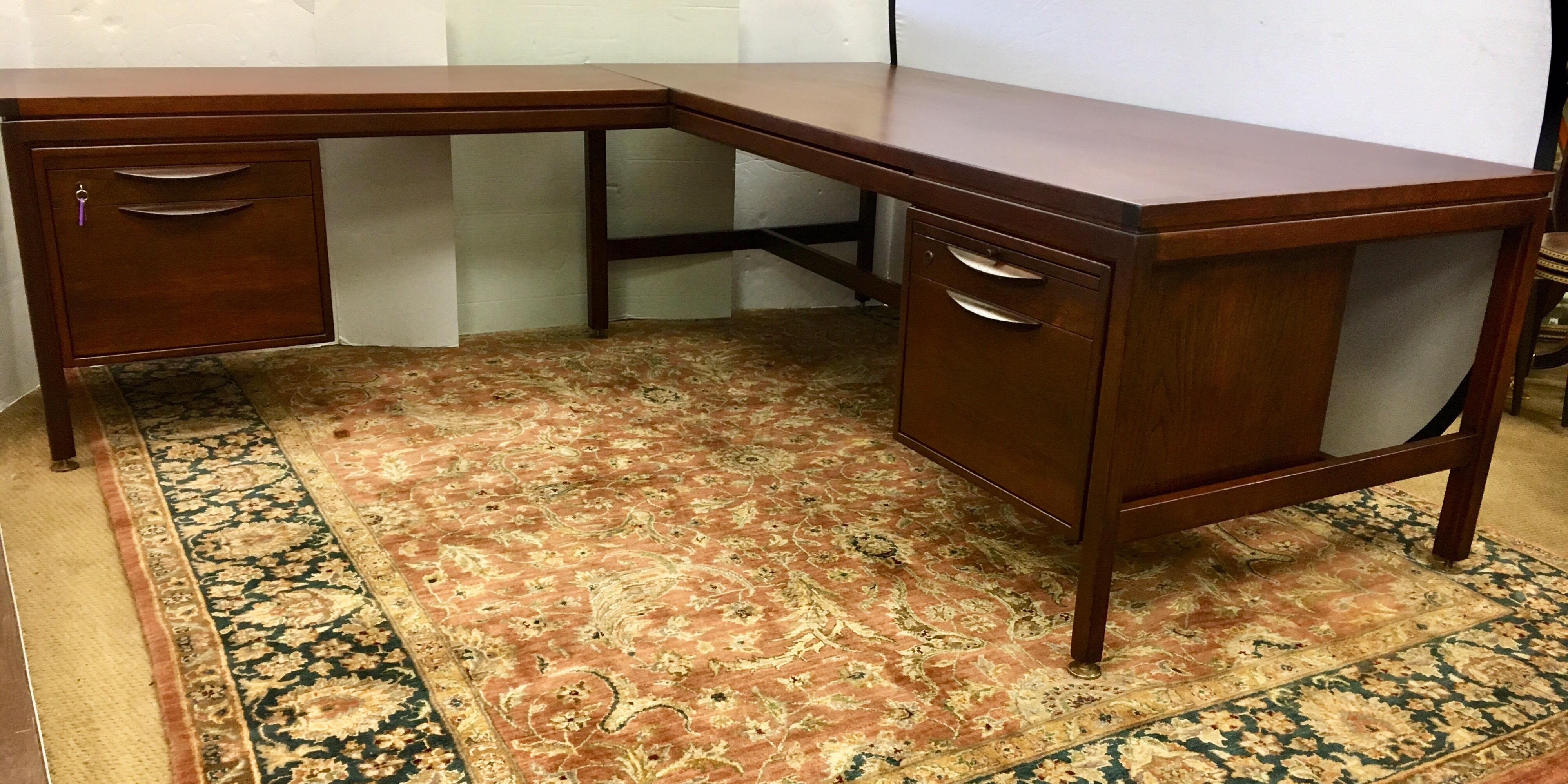 An exceptional Mid-Century Modern two piece walnut executive desk designed by Jens Risom. The desk features gorgeous walnut wood grain and sleek Minimalist design. It offers exceptional storage with multiple drawers including file drawers, a pencil