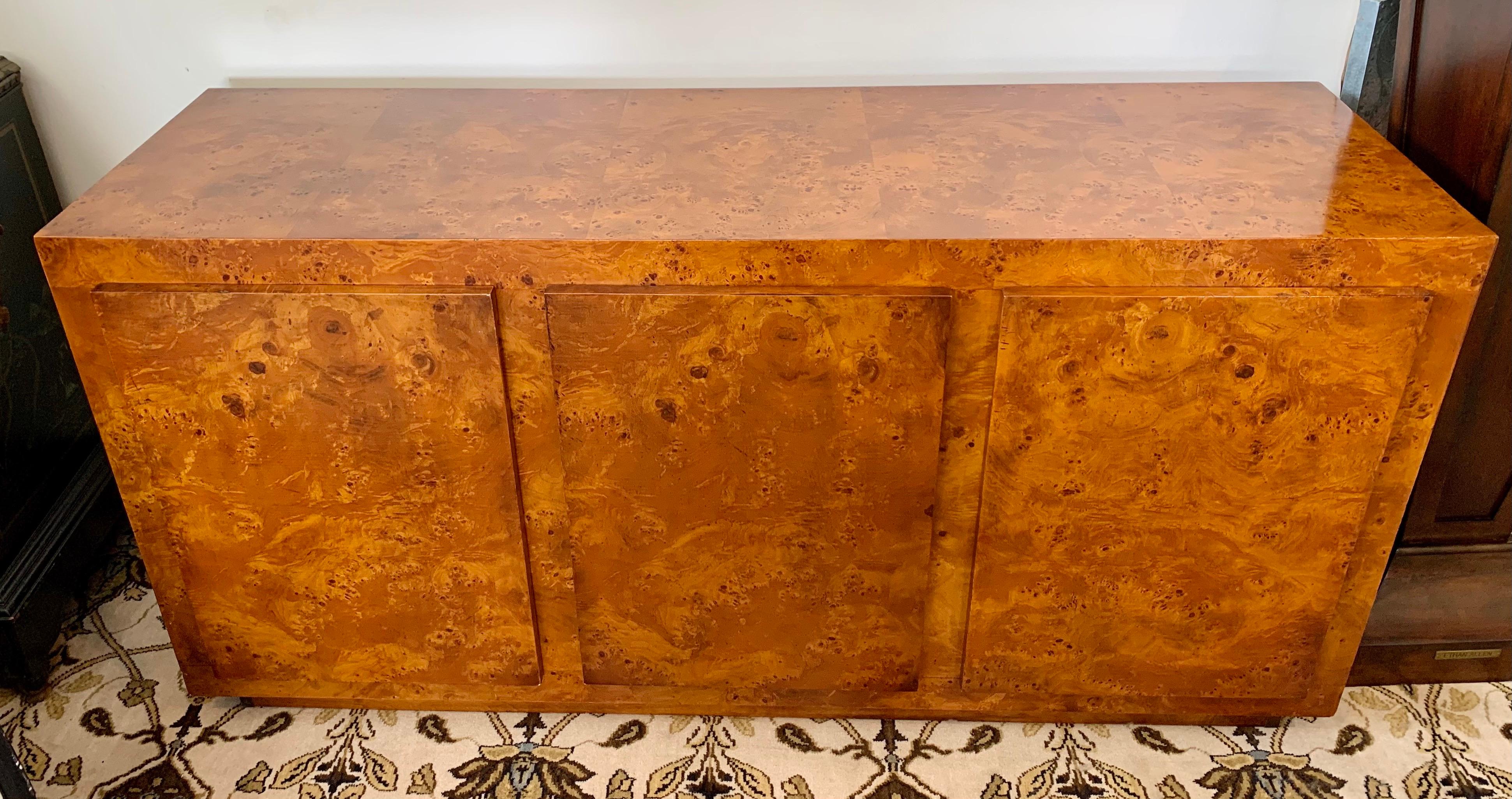 A magnificent John Stuart lacquered burlwood credenza/sideboard/buffet/dresser/dry bar - very versatile and multi-functional! The credenza has ample storage underneath including shelving and three drawers at left. The piece is still in exceptional