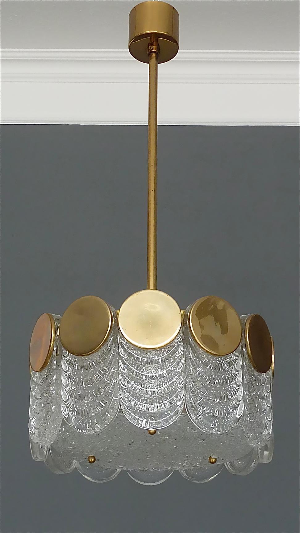 Brutalist Style Mid-Century Modern signed Kaiser drum chandelier/pendant lamp with textured ice-glass petals and patinated brass discs made in Germany, circa 1960-1970. It has twelve 1,5 cm / 0.60 inches thick glass panels and one center glass disc