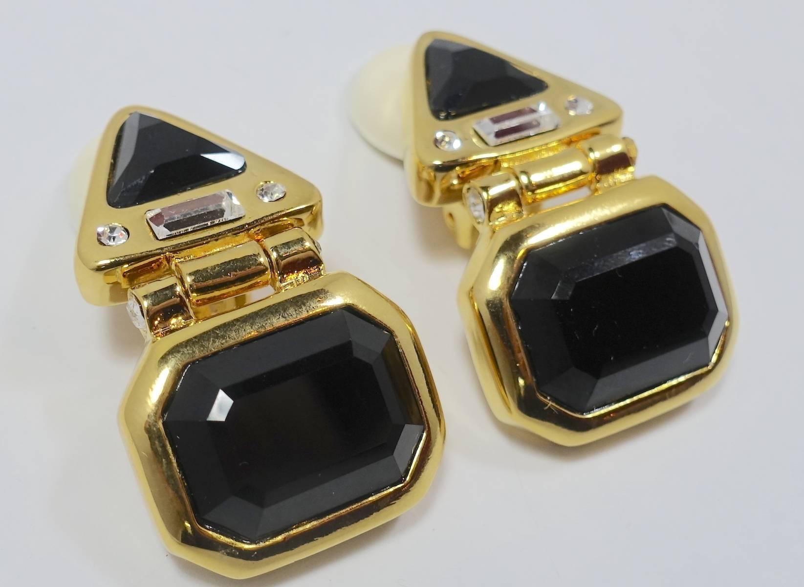 These Kenneth Jay Lane clip earrings feature black and clear rhinestones in a gold tone setting.  These earrings measure 1-5/8” x 7/8” and are signed “Kenneth Lane”. They are in excellent condition.