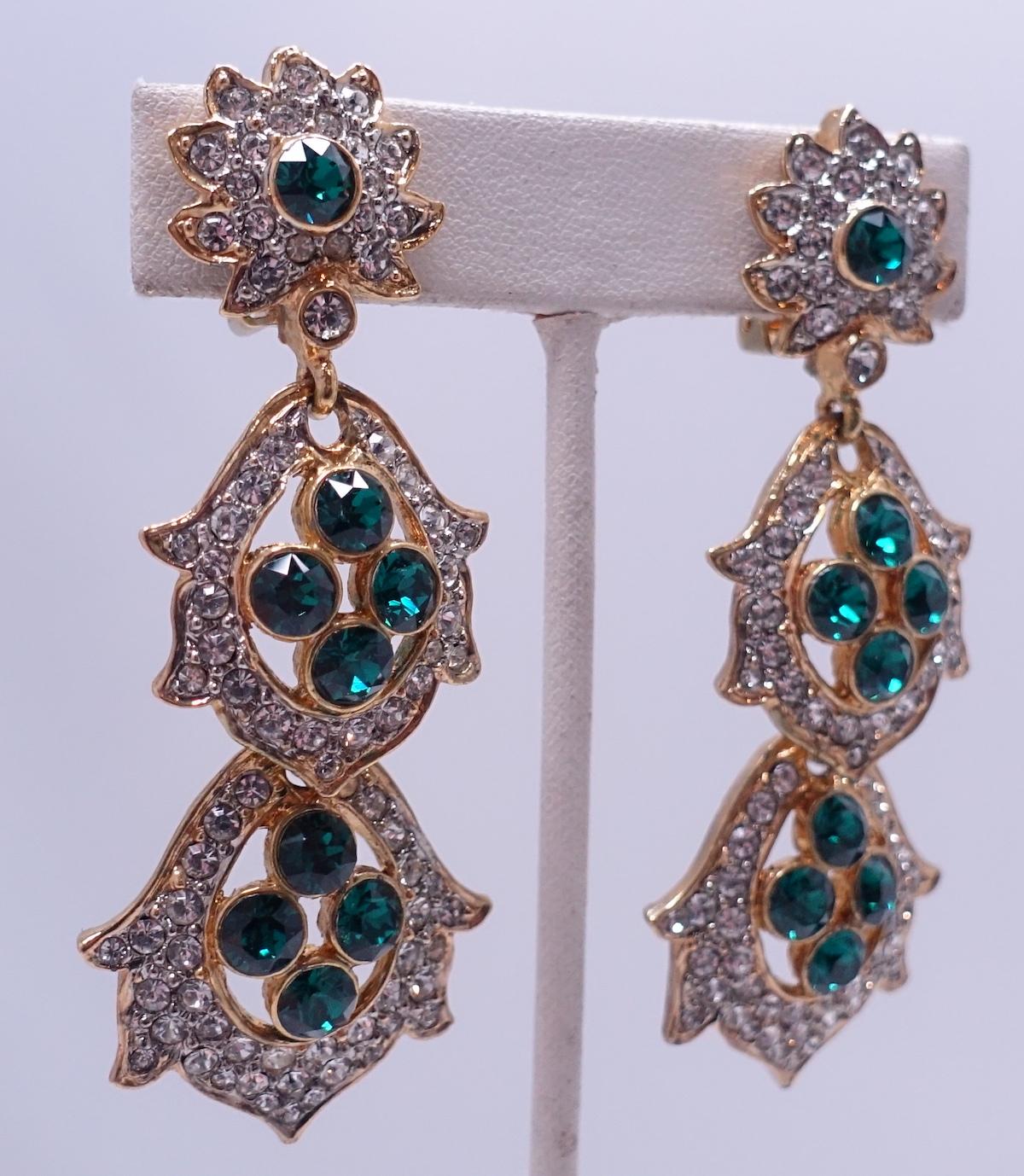 These signed Kenneth Lane drop earrings feature green and clear crystals in a gold tone setting.  In excellent condition, these clip earrings measure 3” long x 1” at bottom and are signed “Kenneth Lane”