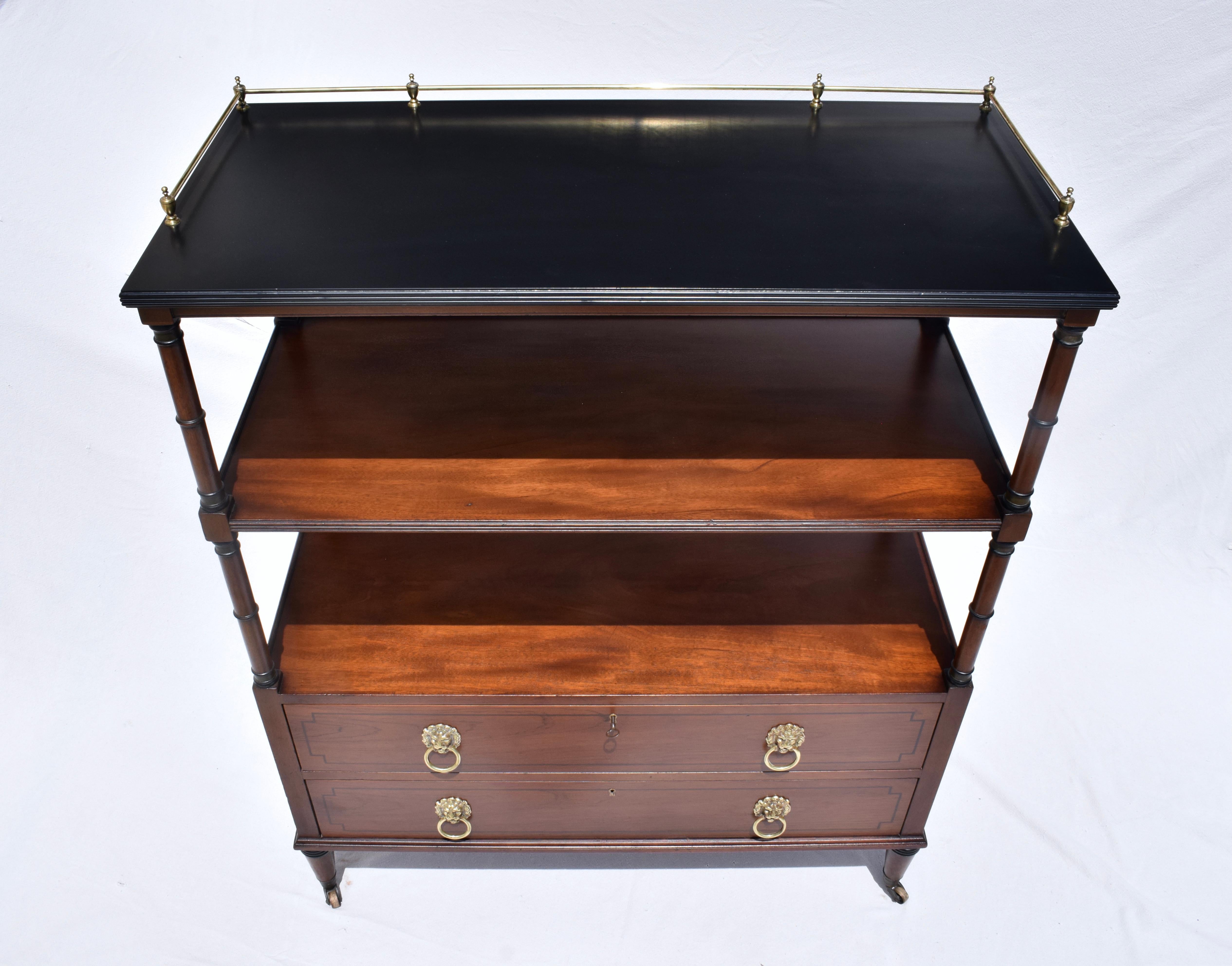 Versatile full body design English Regency style three tier two drawer server handmade in Buffalo, NY by the Kittinger Furniture Company. Set on brass castors with striking lion head brass hardware, this multifunctional piece is entirely moveable