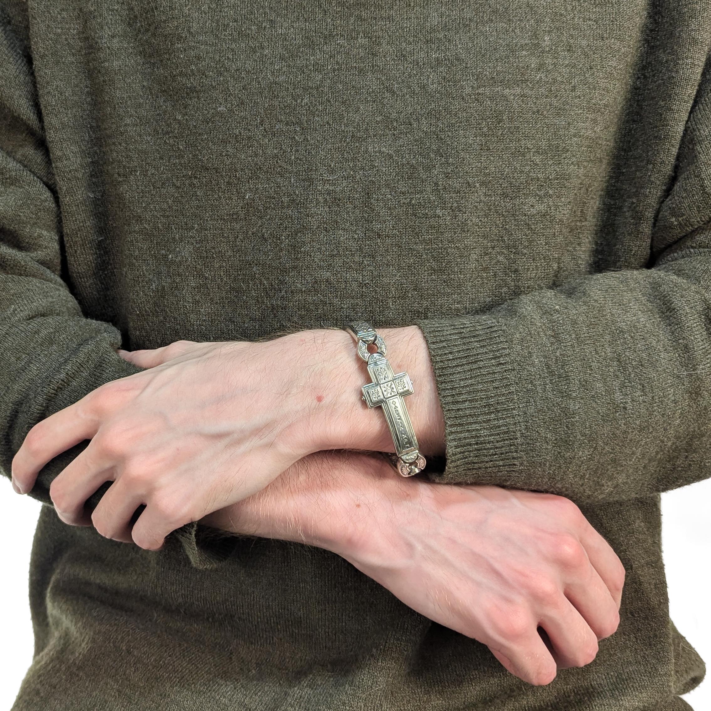 Un raffinato braccialetto d'argento firmato.

Da Konstantino.

In argento sterling.

Dalla serie Dare.

Con una croce in una montatura d'argento incisa. La croce con lettere greche incise sulla parte anteriore.
 
Chiusura con fibbia a