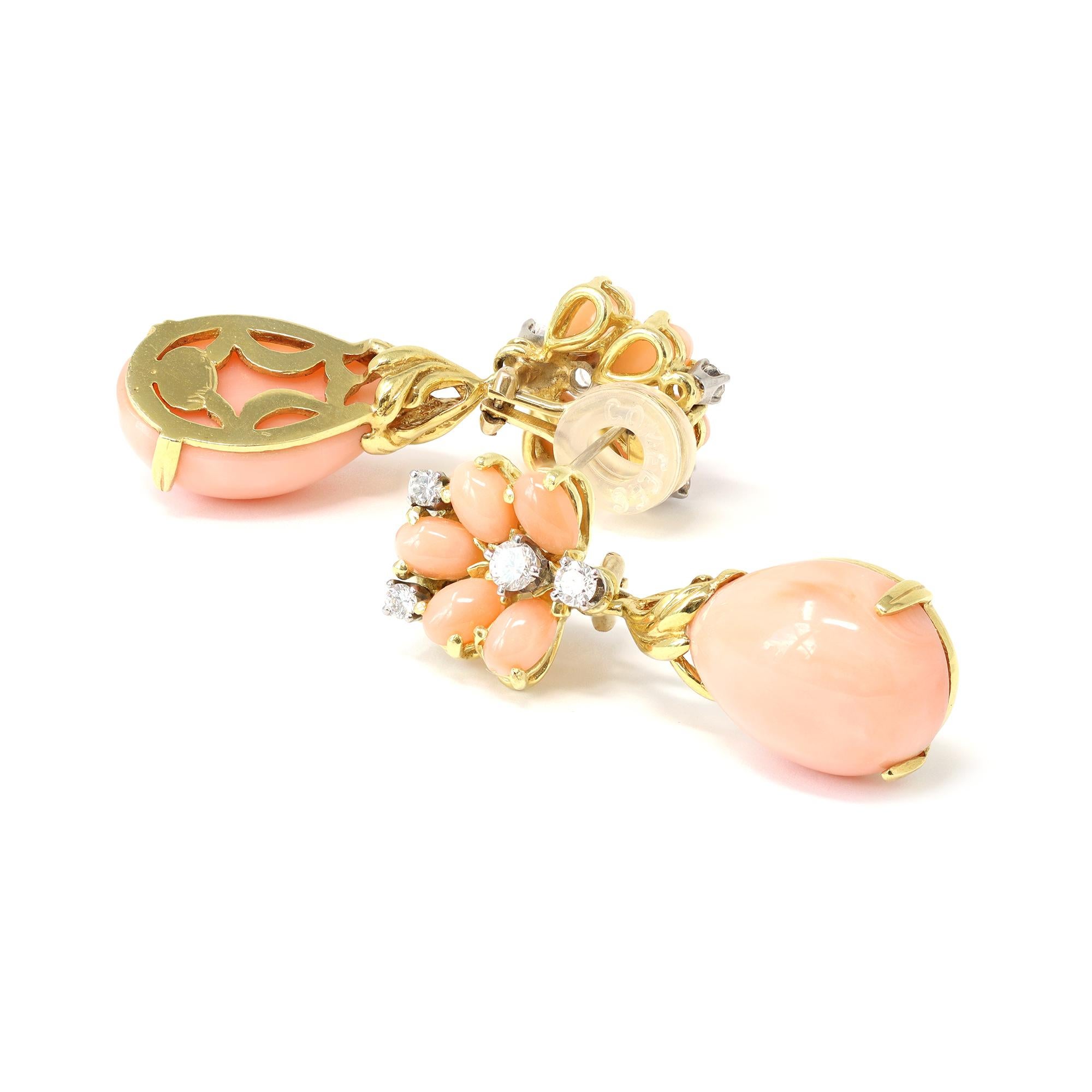 
A rare vintage pair of dangling earrings signed La Triomphe CA 1980. The earrings feature natural Angelskin coral drop pendants with intricate gold design. The coral pendants hang from a cluster of the same coral and diamond tops. The handmade