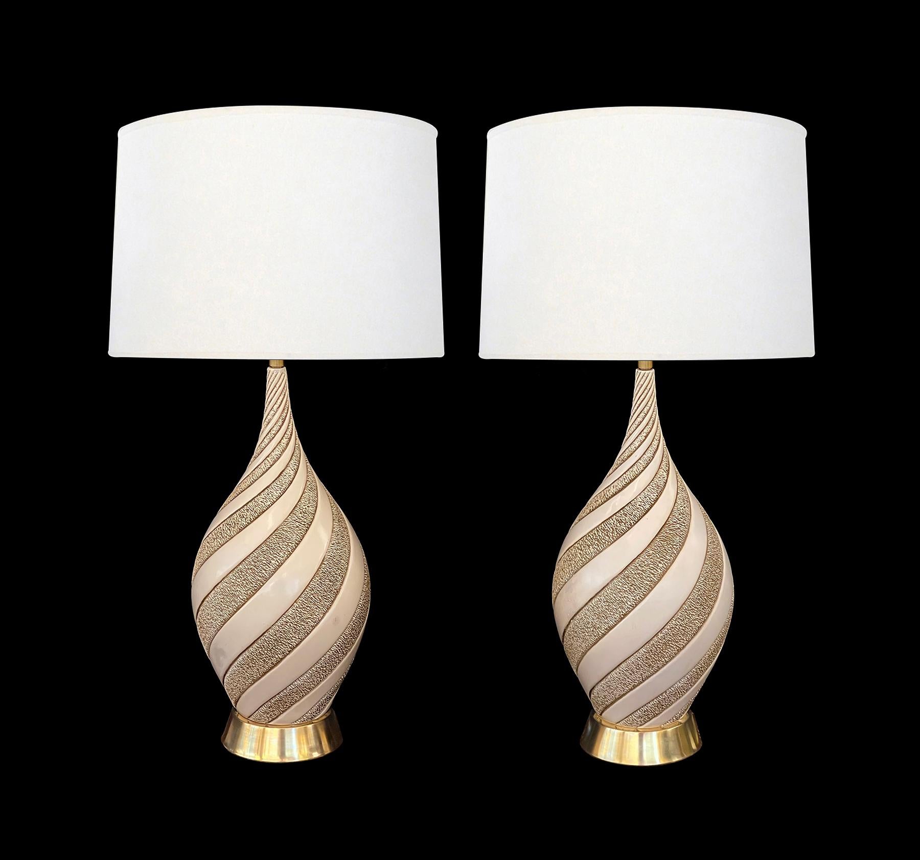 Cada una de las grandes lámparas de escayola en forma de botella con decoración incisa en espiral de franjas alternas texturadas y alisadas; firmadas 