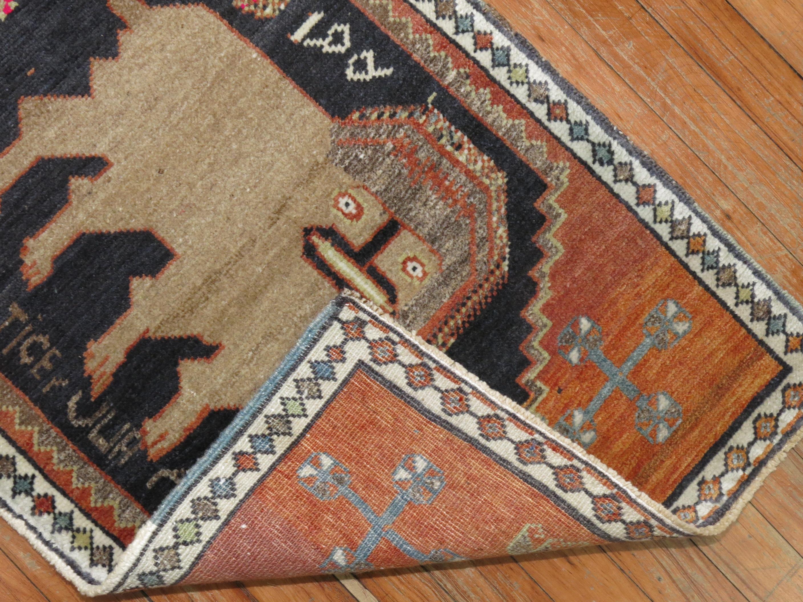 A mid-20th century Turkish rug depicting a stand alone camel color lion on a charcoal medallion and orange field. Weaver inscribed his name under the lion. Pretty Cool, right?

Measures: 1'10