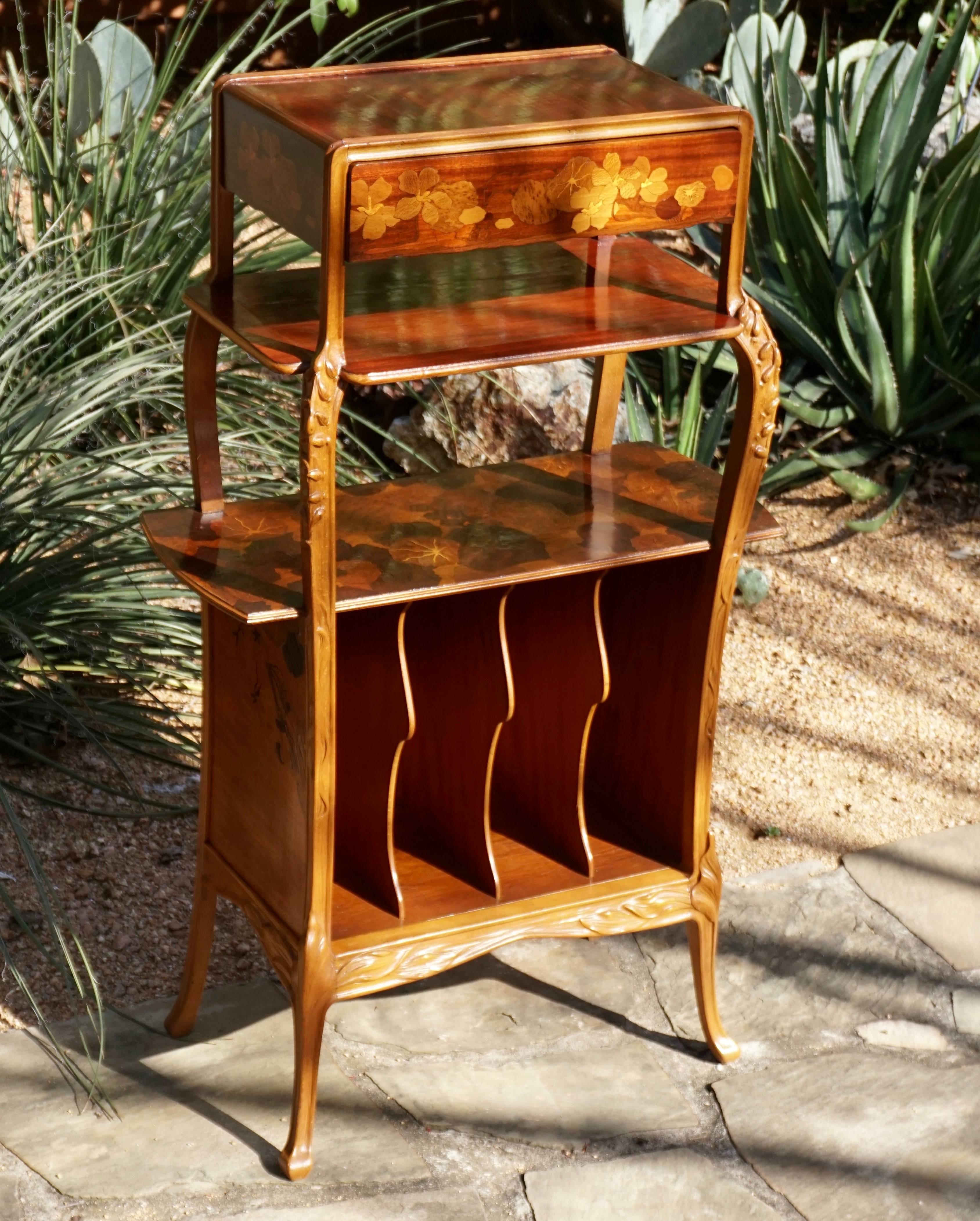 Louis Majorelle Art Nouveau etagere-music cabinet. With marquetry on sides, center and front depicting foliage, vines, flowers and lily pads. One drawer on top, three etageres and decided compartments below. Could be used as a bookcase.

Signed in