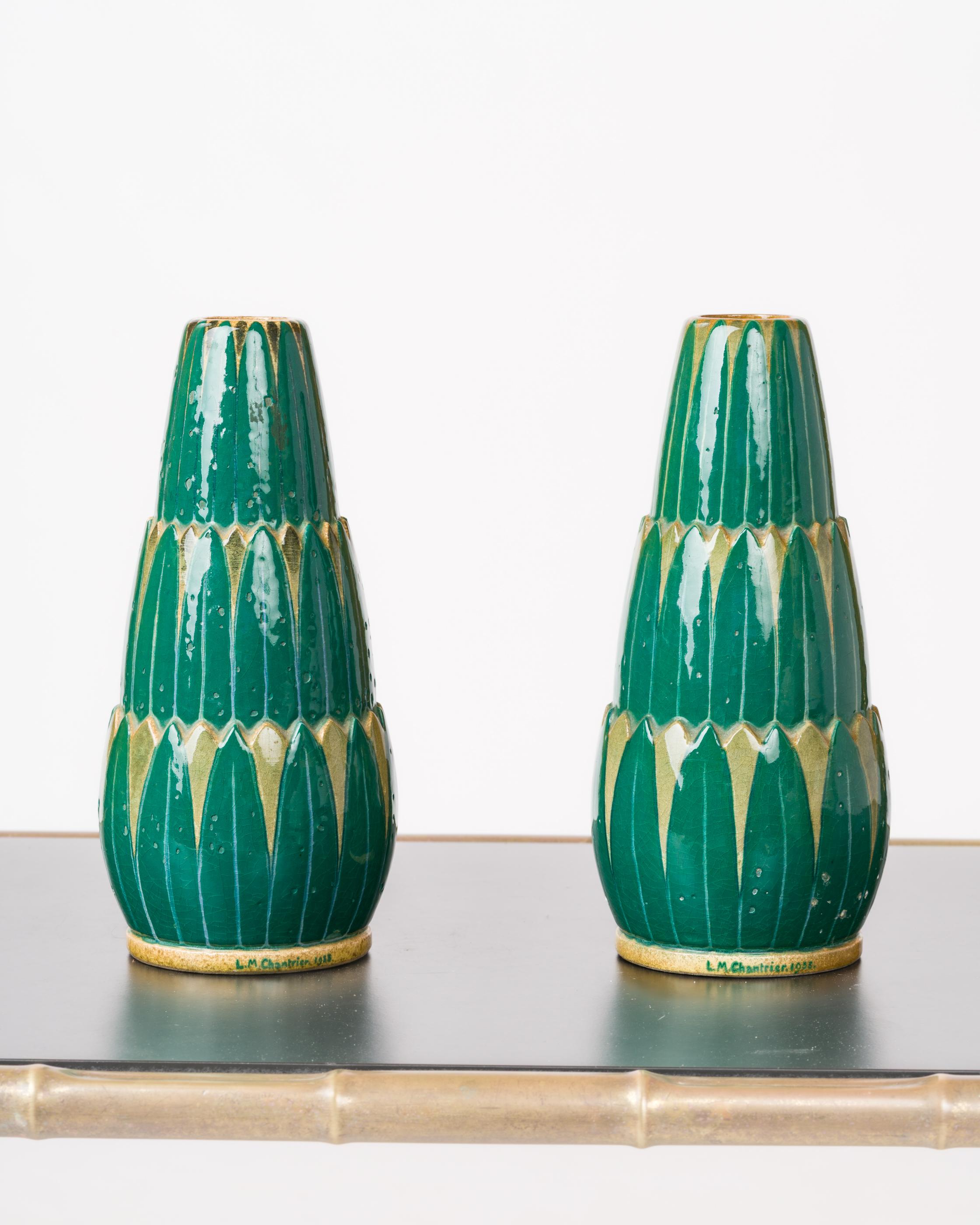 Coppia di vasi in ceramica smaltata con motivi vegetali. Forma oblunga con decorazione a gradini di foglie verdi su sfondo giallo chiaro. La firma dell'artista è presente alla base di ogni vaso. Piccole imperfezioni sulla base, ma praticamente