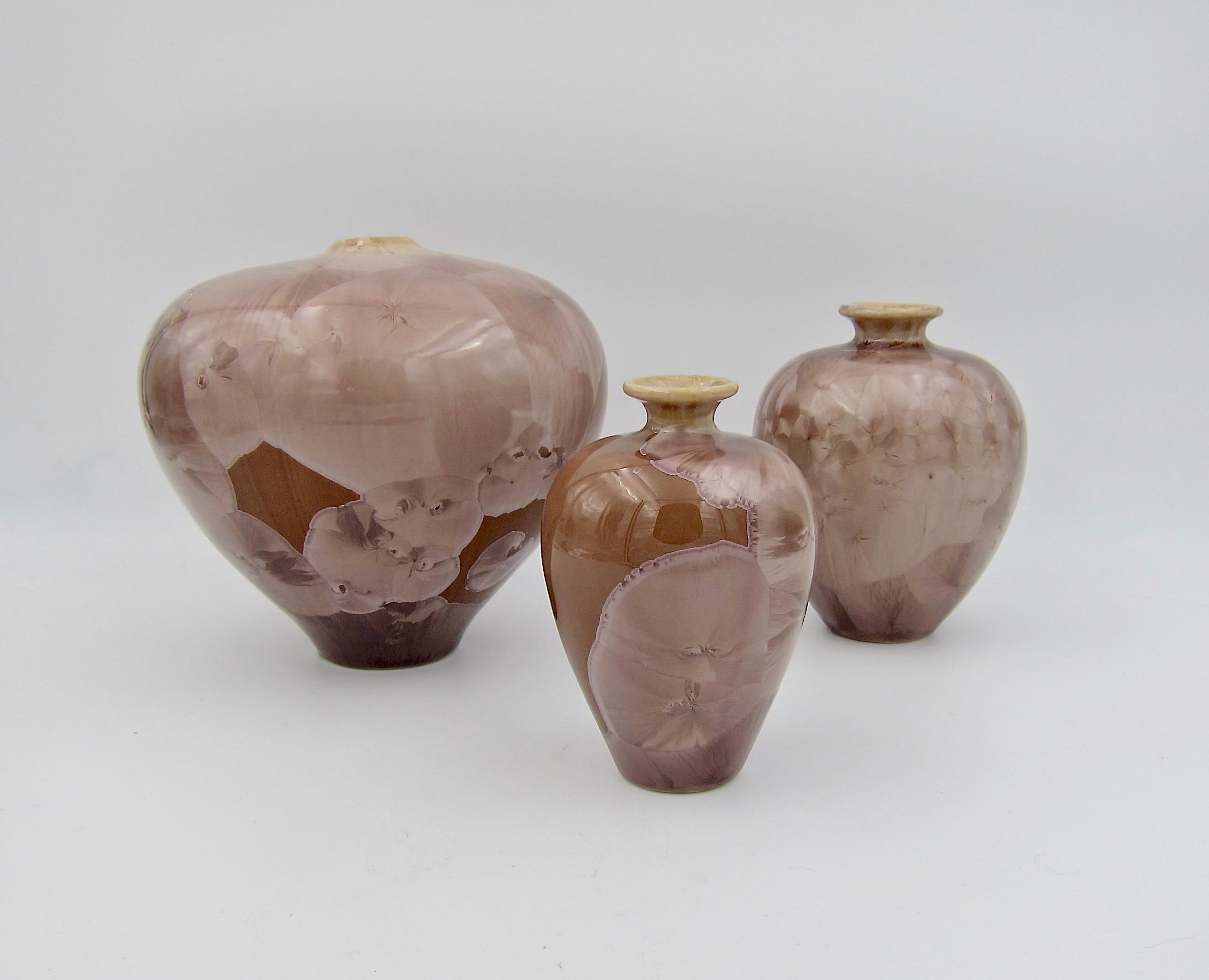 A trio of porcelain vases by Louise Reding of The San Diego Pottery Guild, dating circa 1980s-1990s. Each vase is enveloped in an icy brown glaze -- the color of cappuccino or café au lait. Large and random crystal Formations are Ms. Reding's