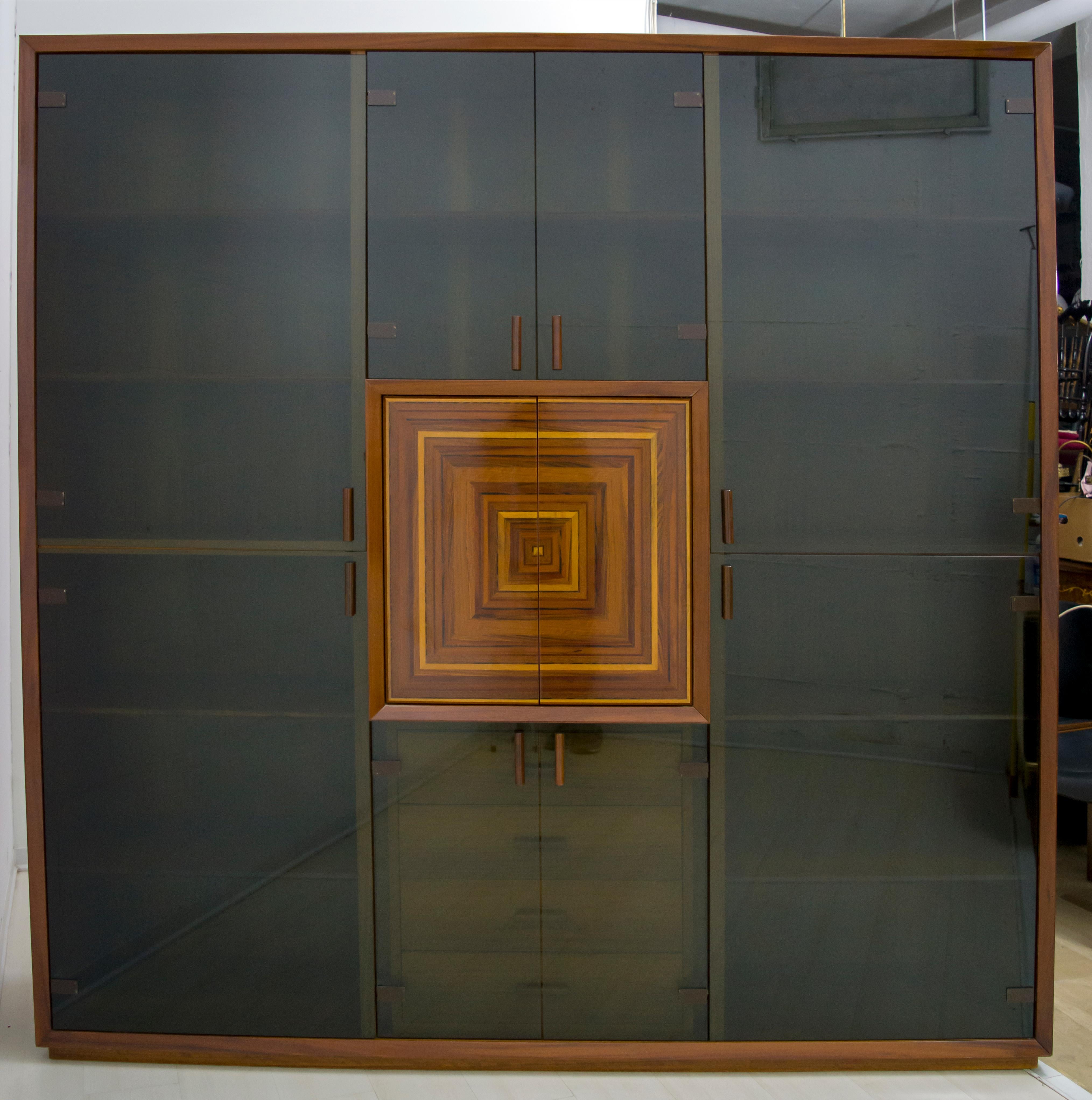 Ce meuble de bar a été conçu par le maître ébéniste Luciano Frigerio et porte une étiquette avec sa signature qui atteste de son authenticité. La marqueterie des portes centrales a été réalisée en bois stratifié plaqué avec des incrustations de bois
