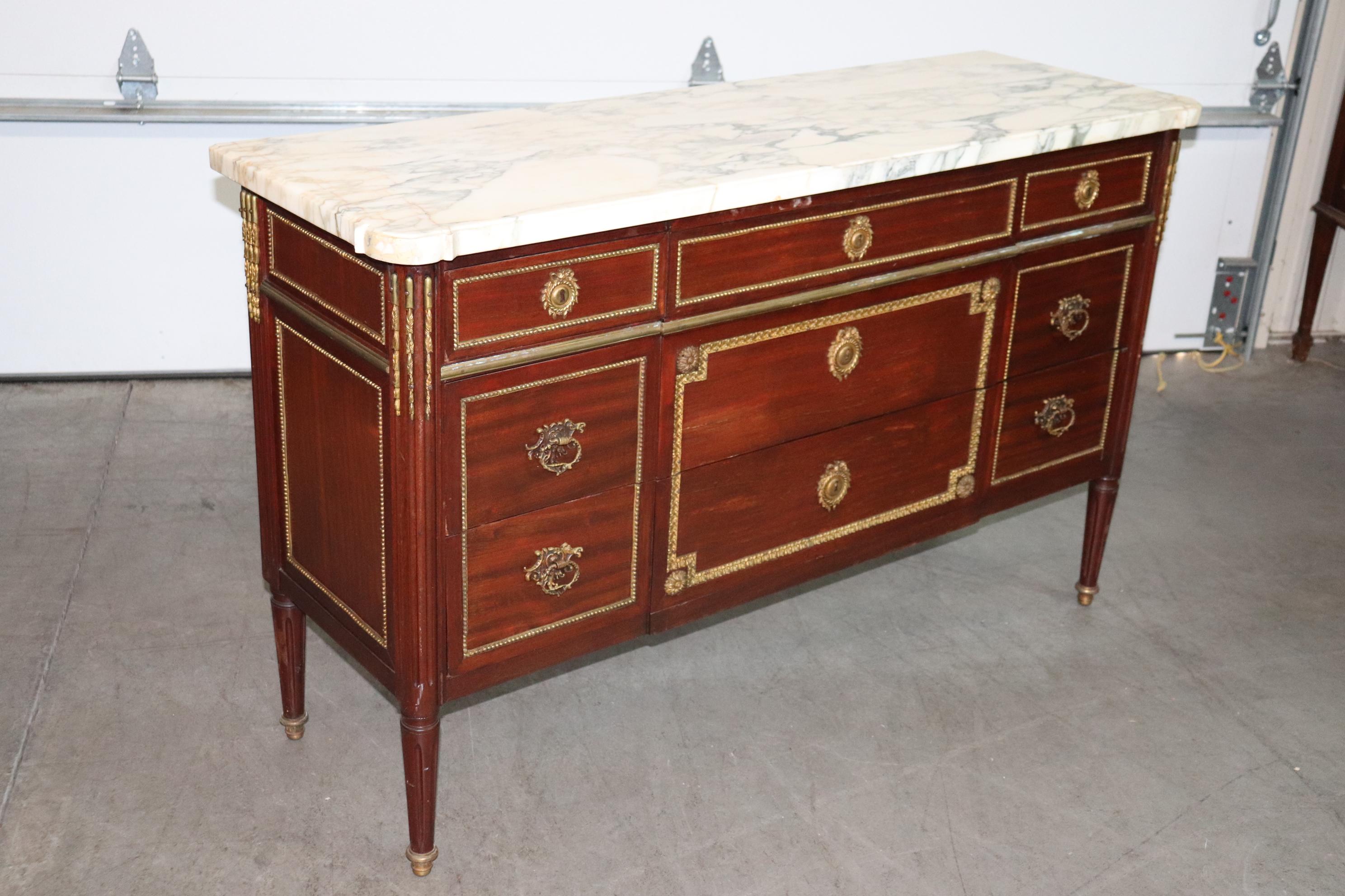 This is a fantastic, entirely original, stamped Maison Jansen commode in very good condition for its age. This 1940-50s era features gorgeous bronze ormolu and a beautiful slab of varigated marble top. The commode is designed with superb proportions