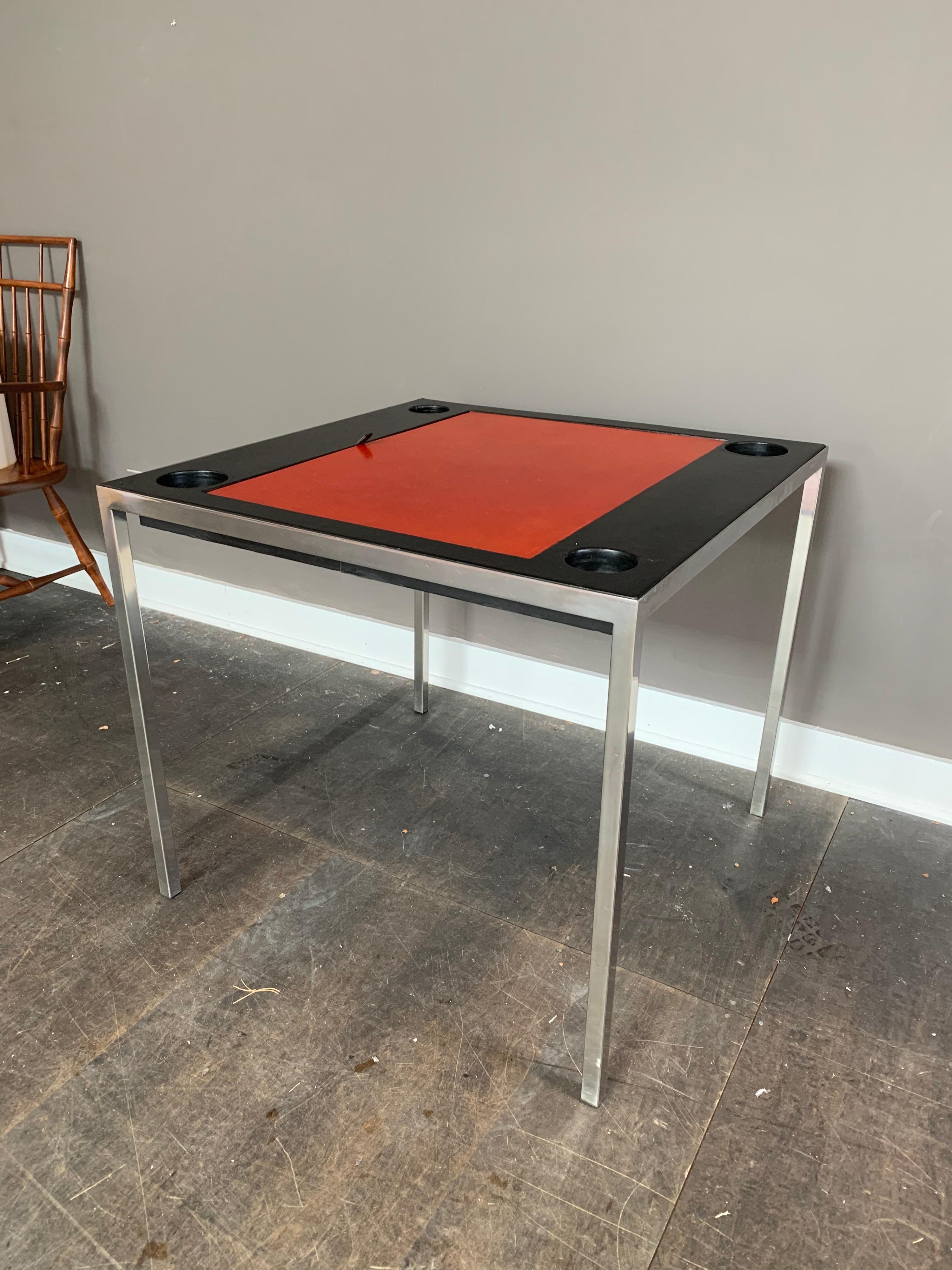 Estampillée Jansen, cette table de jeu de backgammon en acier chromé et cuir noir et rouge, circa 1975, provenance : Malmaison, Roger Prigent Enterprises. Cette belle table a un plateau en cuir rouge qui s'ouvre sur l'aire de jeu du backgammon. Bien