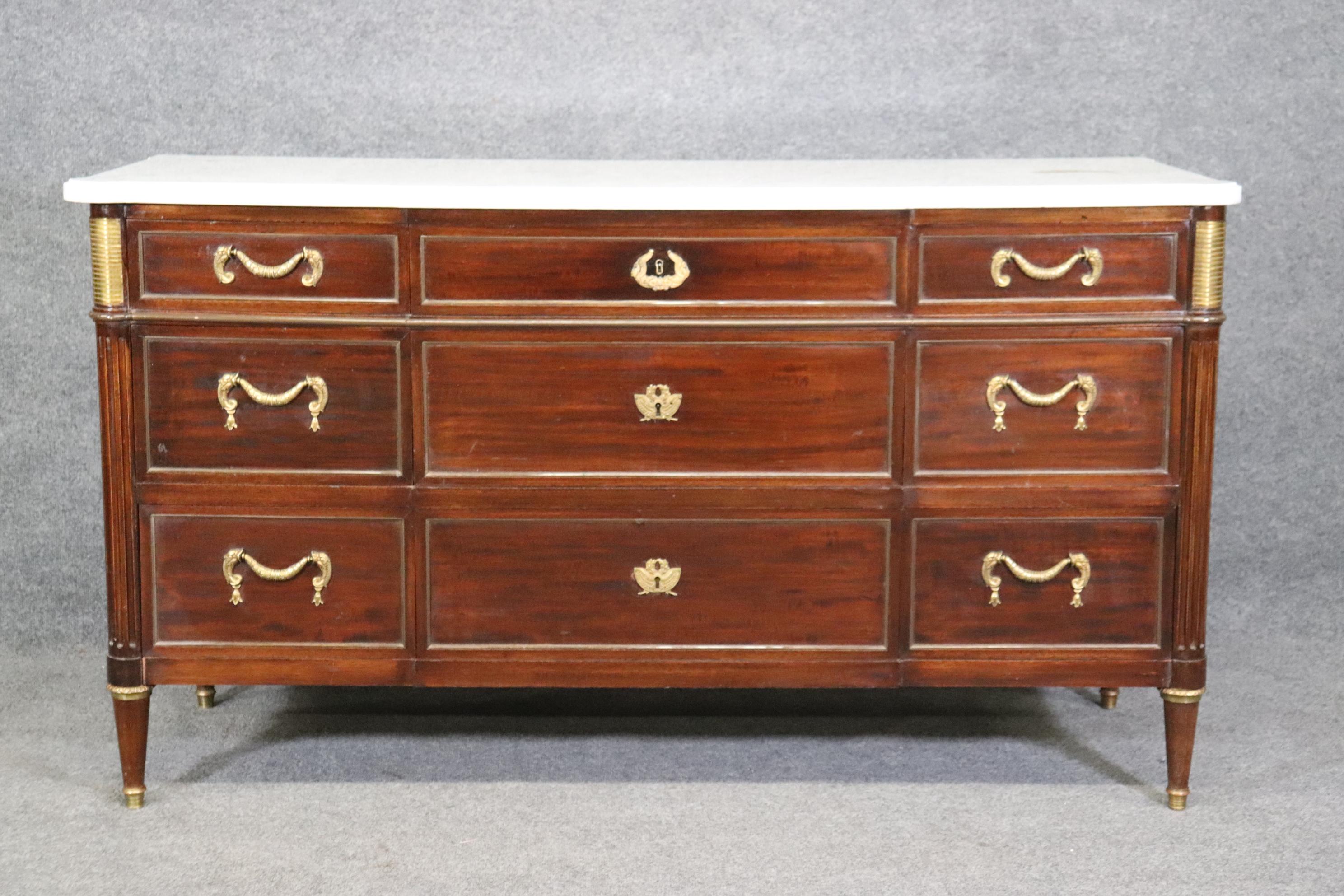 This is a fantastic signed Maison Jansen 9 drawer marble top dresser or commode. The piece features superb cast bronze and brass ormolu and a white carara marble top. The mahogany case is solid mahogany and the piece is in good condition and does