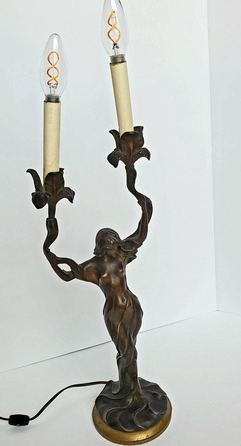 A rare and exceptional Art Nouveau period French bronze figural sculpture, converted to a table lamp. Signed in cast on base. Marcel Debut (France, 1865-1933), circa 1900. 

Depicting a beauty draped in flowing robes, holding two elongated flowers