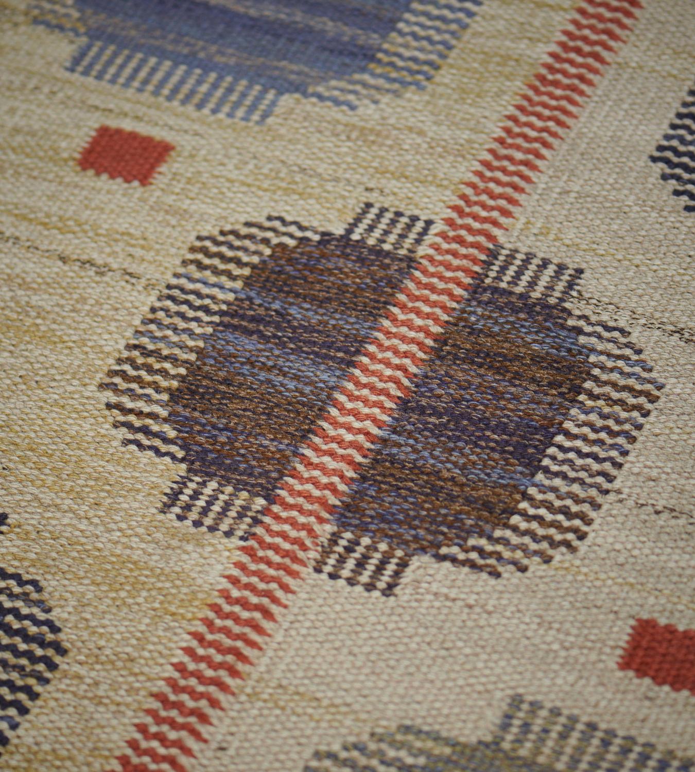 This vintage handwoven Swedish rug has an overall ivory oat field with diagonal rows of stylized graphic geometric pendants, interrupted by a delicate complementary rust stripe. Signed by the original workshop.

About the master weaver:
The