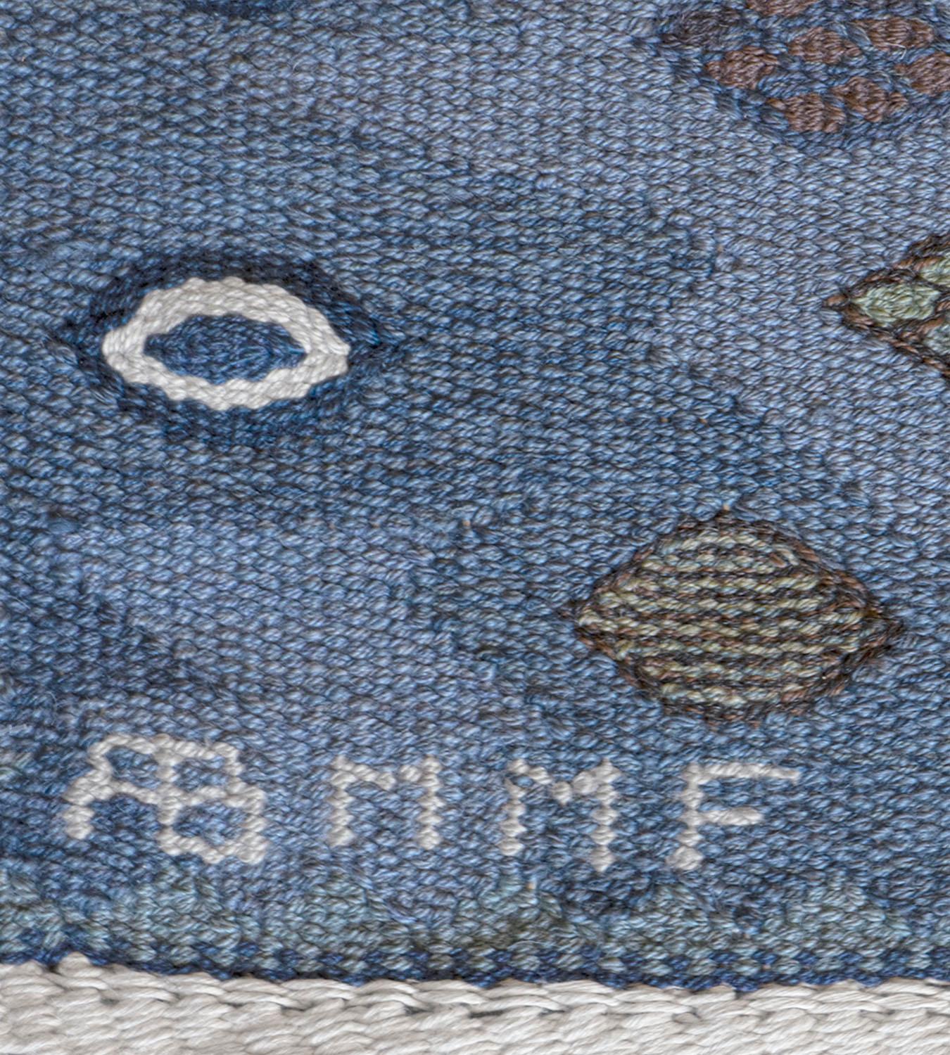 Ce tapis suédois tissé à la main présente un champ nuancé de bleu, de taupe et de brun violet avec des bandes horizontales de petits losanges polychromes entourant de larges bandes contenant de grands losanges dentelés reliés entre eux, chacun