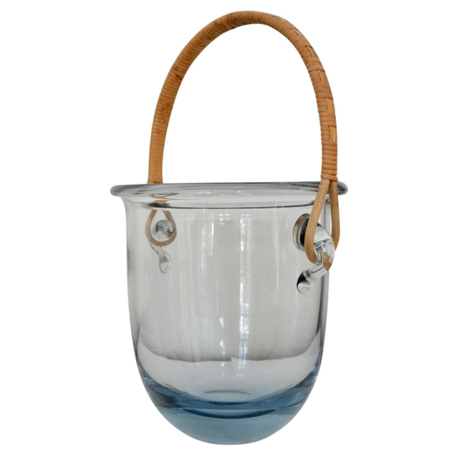 This large ice bucket is probably by Jacob E. Bang, and manufactured by Holmegaard in Denmark. It has a rattan handle and is signed, but not very easy to read.