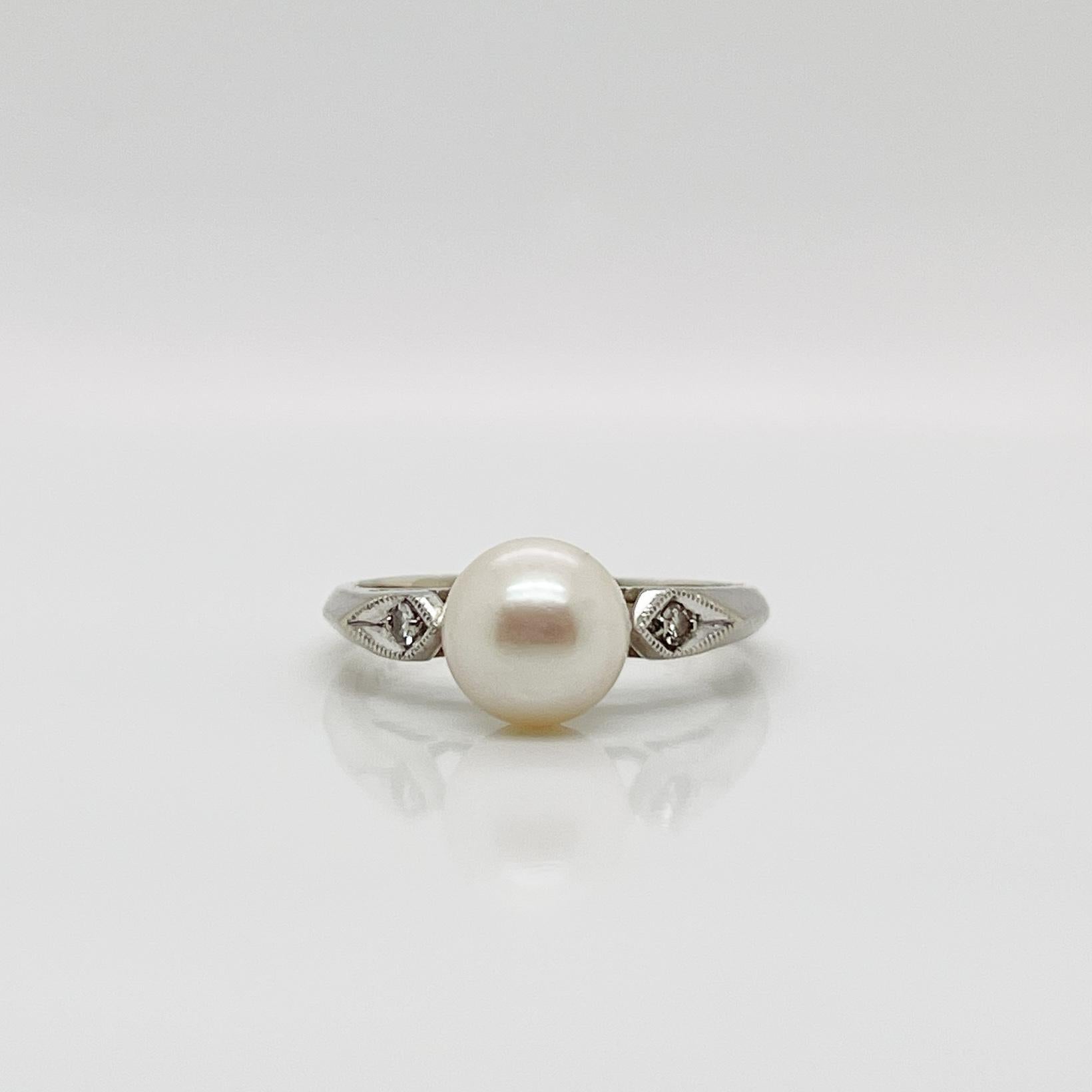A fine Retro signed pearl cocktail ring.

In 14k white gold.

Set with 7mm round white pearl and flanked by two small accent diamonds on the shoulder of the setting.

Marked to the shank for Rothman & Schneider of New York City.

Simply a wonderful