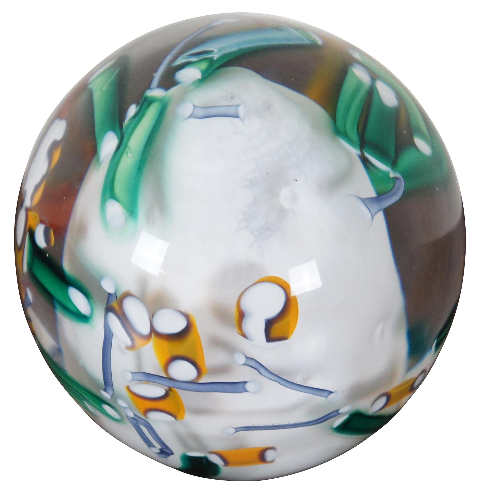 Vintage signed art glass paperweight orb featuring abstract shapes in white, green, blue and orange.
 