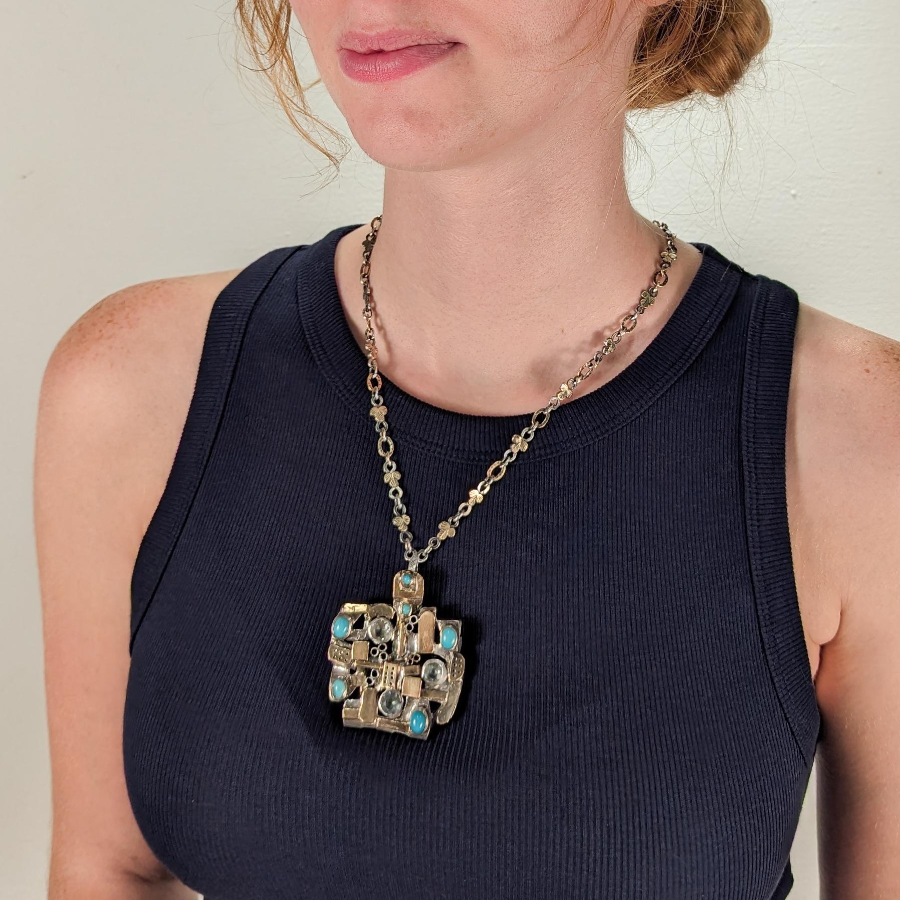 Una fina combinación convertible de collar colgante modernista y broche.

De la orfebre modernista neoyorquina Resia Schor. 

En plata de ley, oro de 14k y engaste en bisel con múltiples piedras preciosas

Compuesto por un gran colgante y un collar