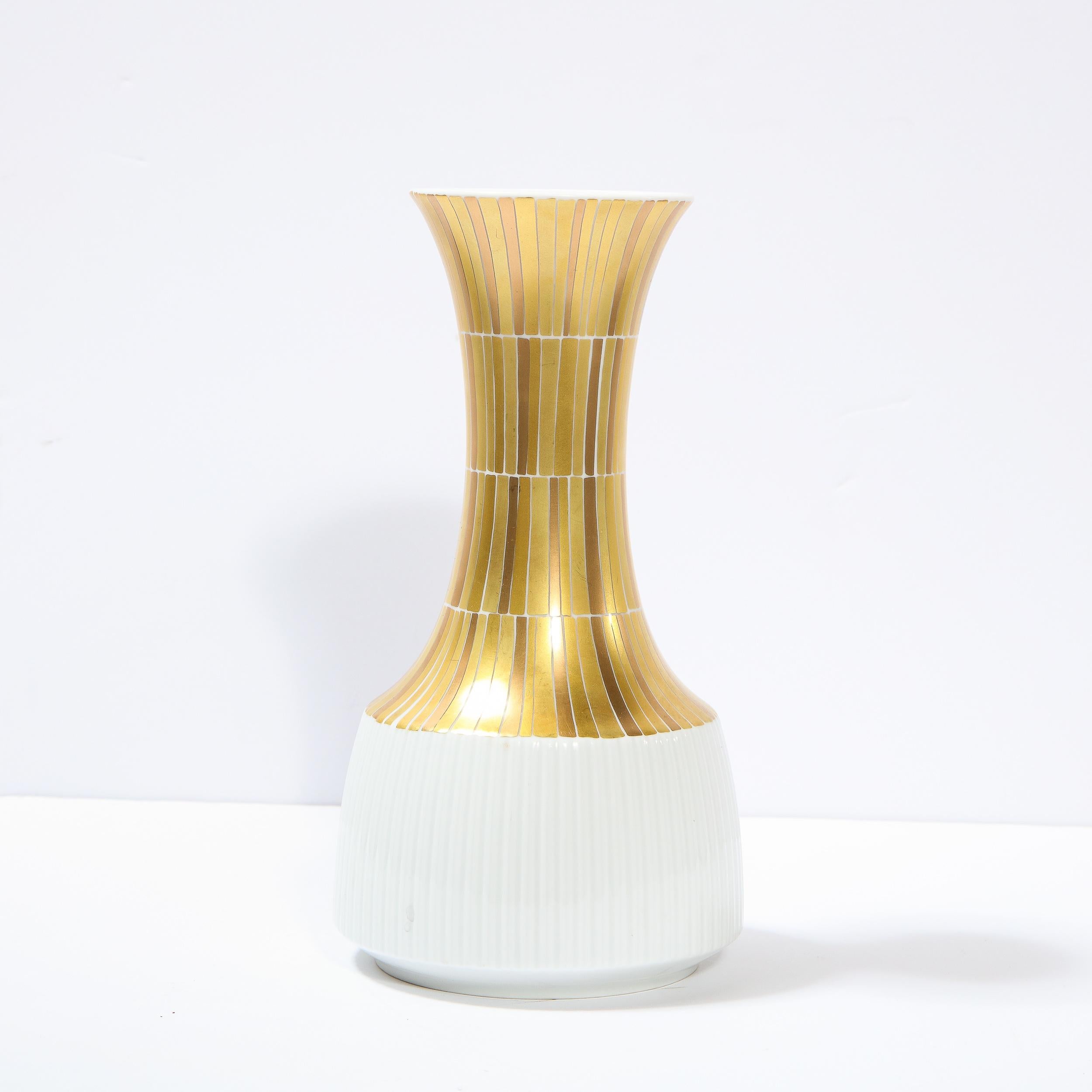 This beautiful porcelain vase was realized by the esteemed designer Tapio Wirkkala for Rosenthal in Germany, during the latter half of the 20th century. It features a white channeled base; an hourglass form neck with rectilinear 24kt gold detailing;