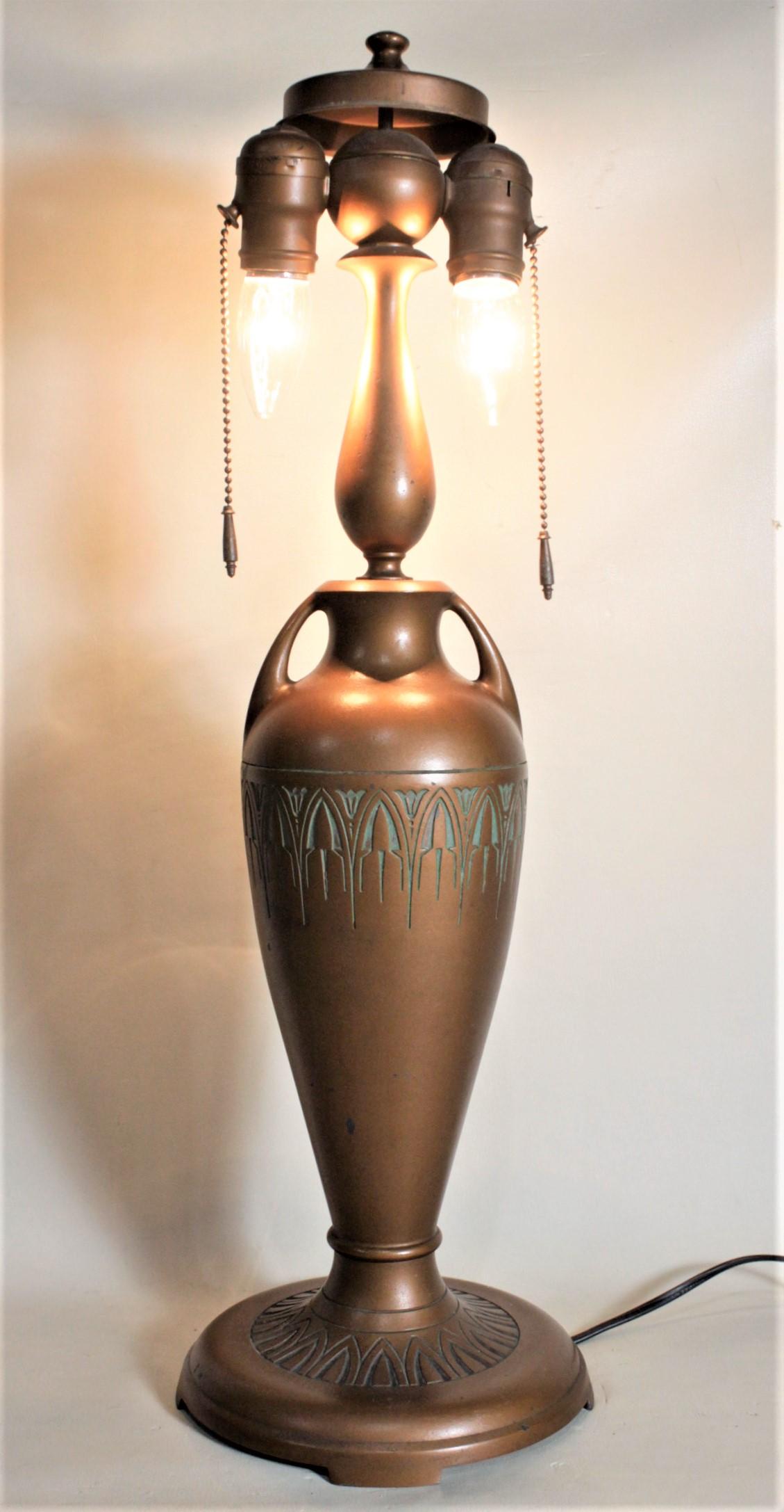 This patinated metal table lamp base was made by the Moe Bridges Company of the United States in approximately 1920 in the Arts & Crafts style. The base has double light sockets at the top with the original pull chains and weights and a nicely