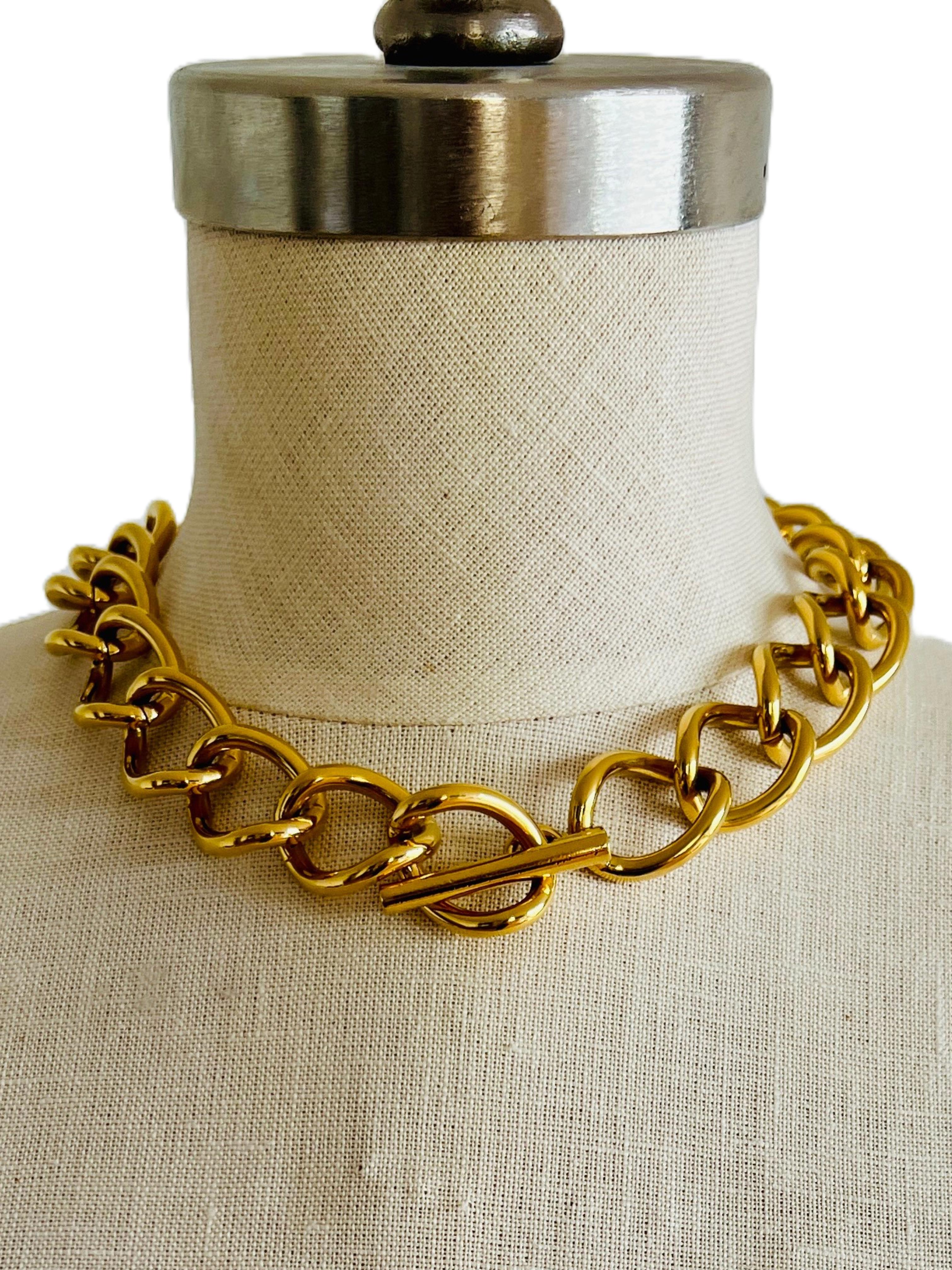 This vintage Monet necklace is a testament to exceptional craftsmanship, offering a weighty, substantial feel reminiscent of fine jewelry with the look and feel of real 14k gold. The bold, gold-tone chain showcases large interlocking links, exuding