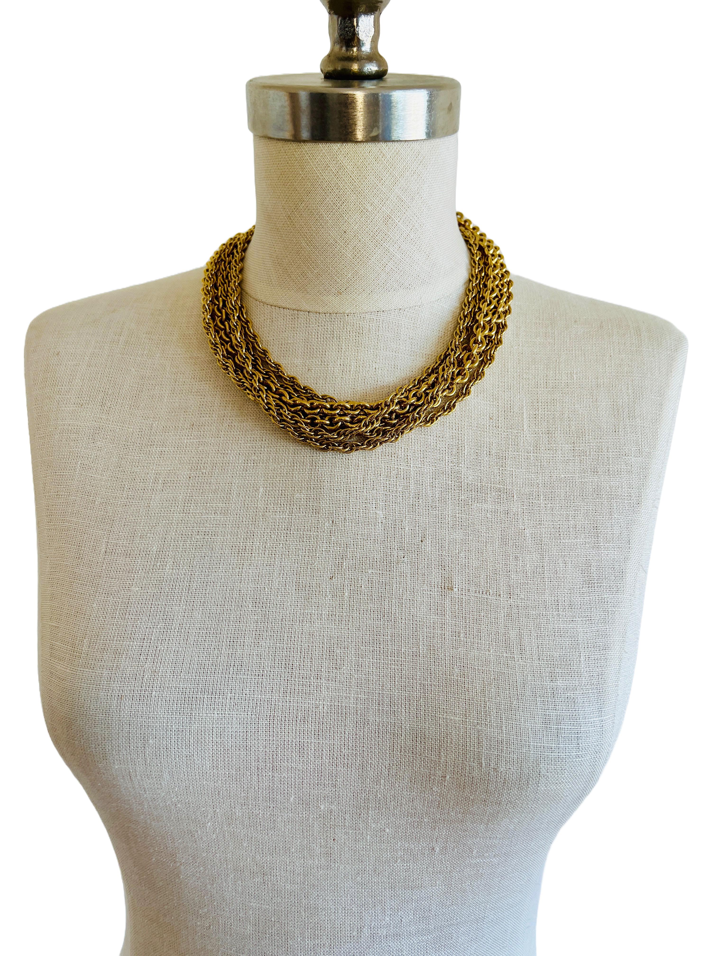 This vintage Monet necklace is a true runway-worthy statement piece, designed to captivate with its bold multi-chain construction. Featuring a stunning combination of smooth rolo chains and intricately twisted rope chains, this luxurious necklace