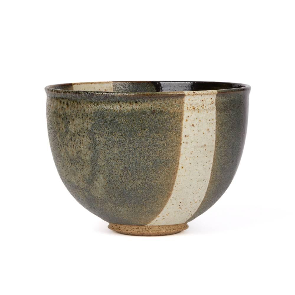 A very stylish rounded Studio Pottery bowl of simple form standing raised on a narrow rounded unglazed foot decorated in banded sections of grey, white and black glazes with a speckled stone finish. The bowl has a raised artist seal mark applied to