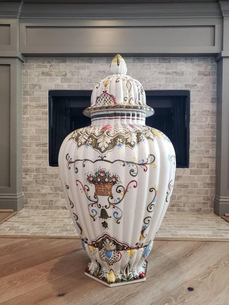 A magnificent and impressive sized vintage Italian hand painted lidded Fiori urn form vase. Exquisitely polychrome decorated floral, scrollwork motif, rich color, shaped top surmounted with large finial, hexagonal base, signature, elegantly aged
