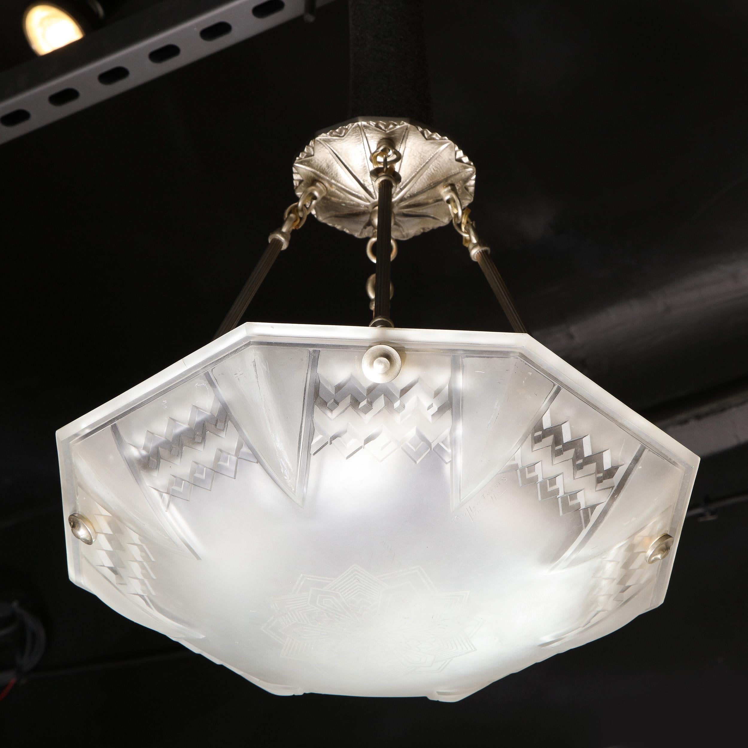 This elegant Art Deco chandelier was realized by the celebrated maker Muller Frères in Luneville, France, circa 1930. It features a subtly concave octagonal form in frosted glass with a double layered cubist diamond motif tracing the perimeter of