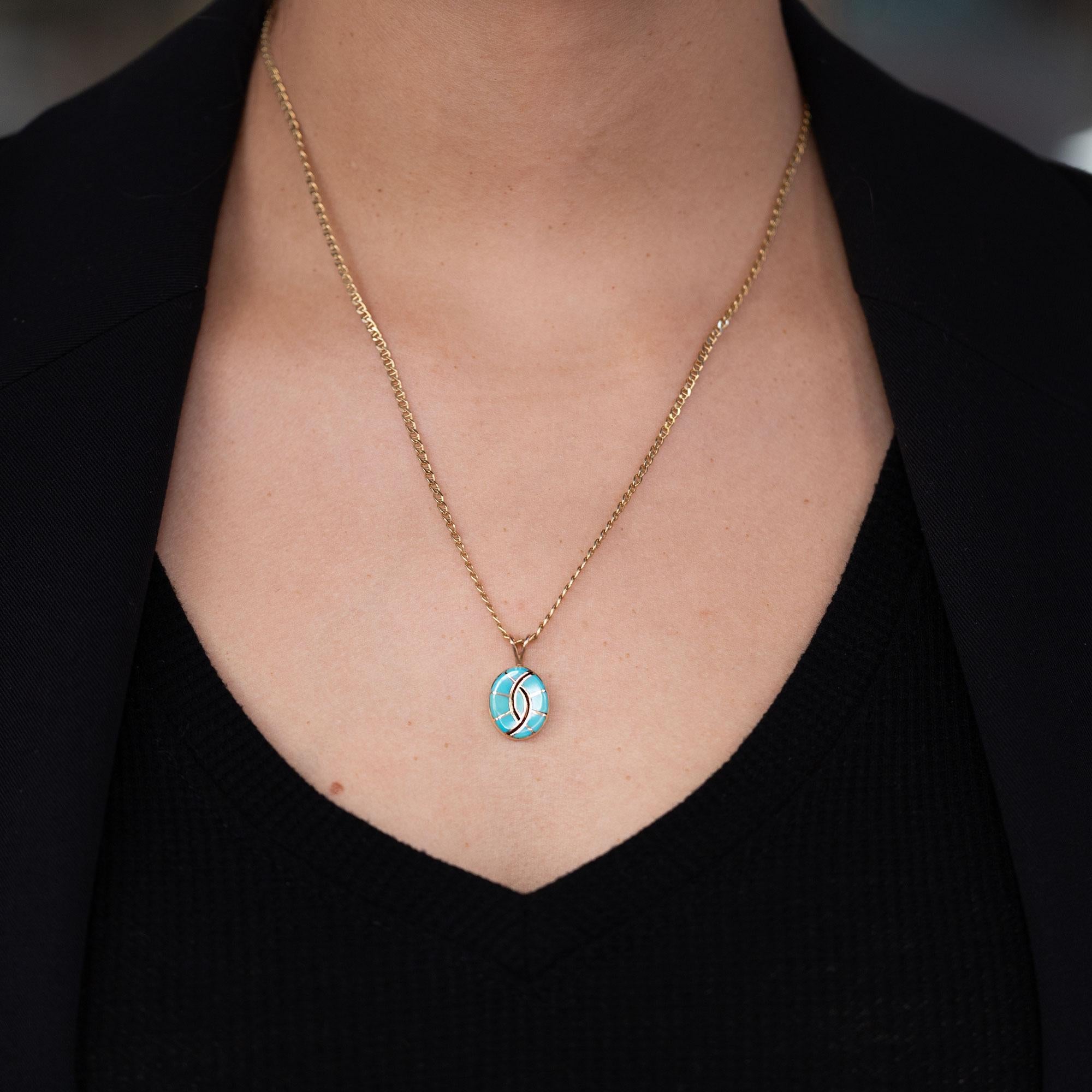 Collana vintage con ciondolo dei nativi Zuni (forse Navajo) e turchese proveniente dalla famosa miniera di Kingman, in Arizona, rinomata per il suo colore blu-verde puro. Intricatamente incastonato in una cornice ovale in oro giallo 14k, il design