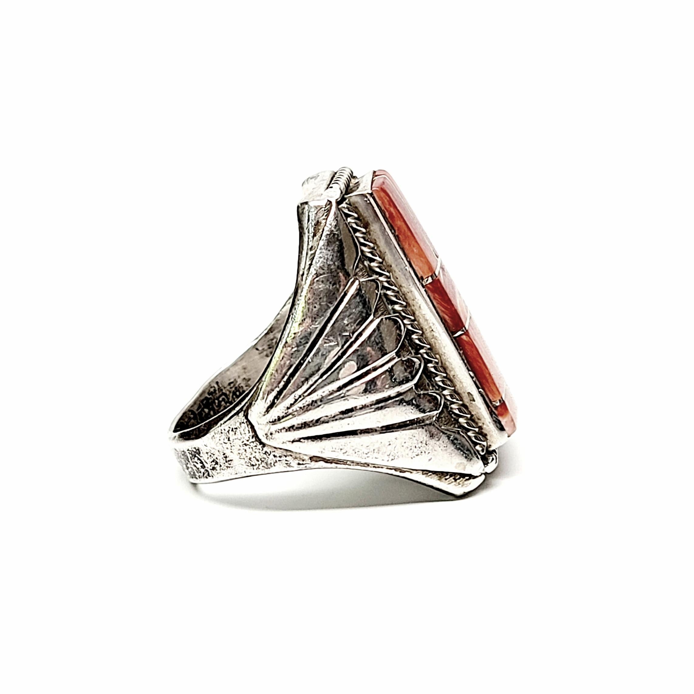Signed CW Native American sterling silver and spiny oyster men's channel inlay ring.

Size 12

Features beautiful and intricate channel inlay of spiny oyster in a large and substantial ring with rope textured frame and metal overlay