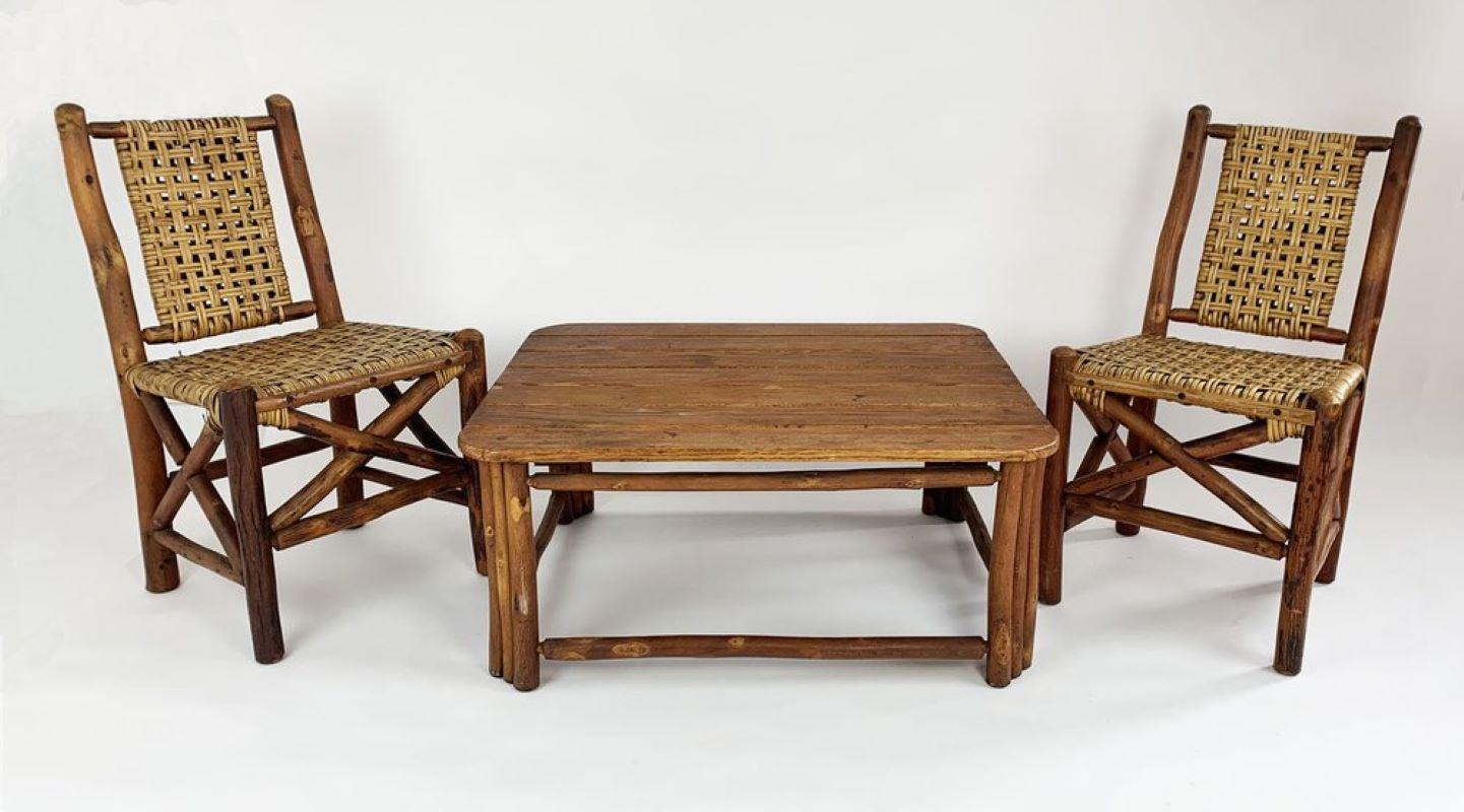 This Old Hickory coffee table has a seven-board oak slat top and a hickory pole base with upper and lower stretchers around the perimeter. Its most attractive and unusual feature is the design of its legs, each of which comprises three stacked