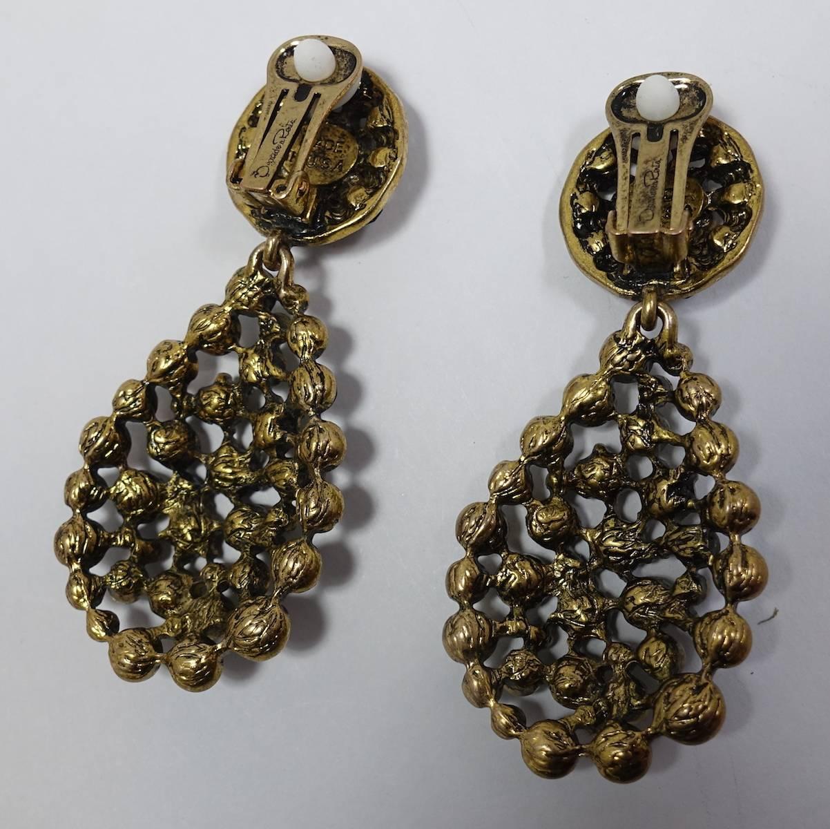 These Oscar de la Renta earrings feature green rhinestones in a gold tone metal setting.  They measure 2-7/8” x 1-1/4” and signed “Oscar de la Renta”.  These earrings are in excellent condition.