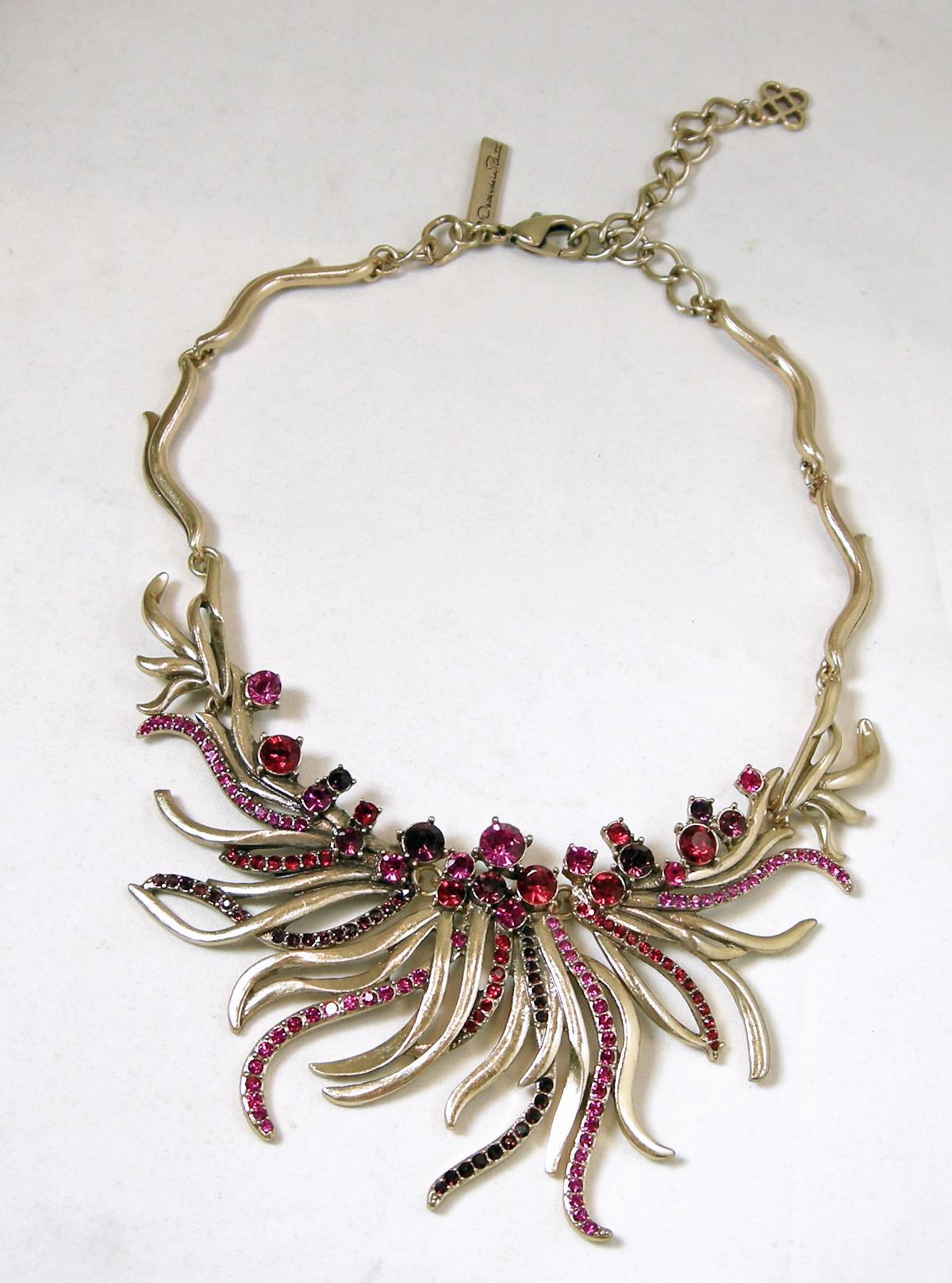 This signed Oscar de la Renta necklace has a mixture of  red, pink & amethyst crystals in a gold tone setting.  This necklace measures 17-1/2” long with a spring clasp.  The front centerpiece is 2-1/2” top to bottom.  This necklace is signed “Oscar