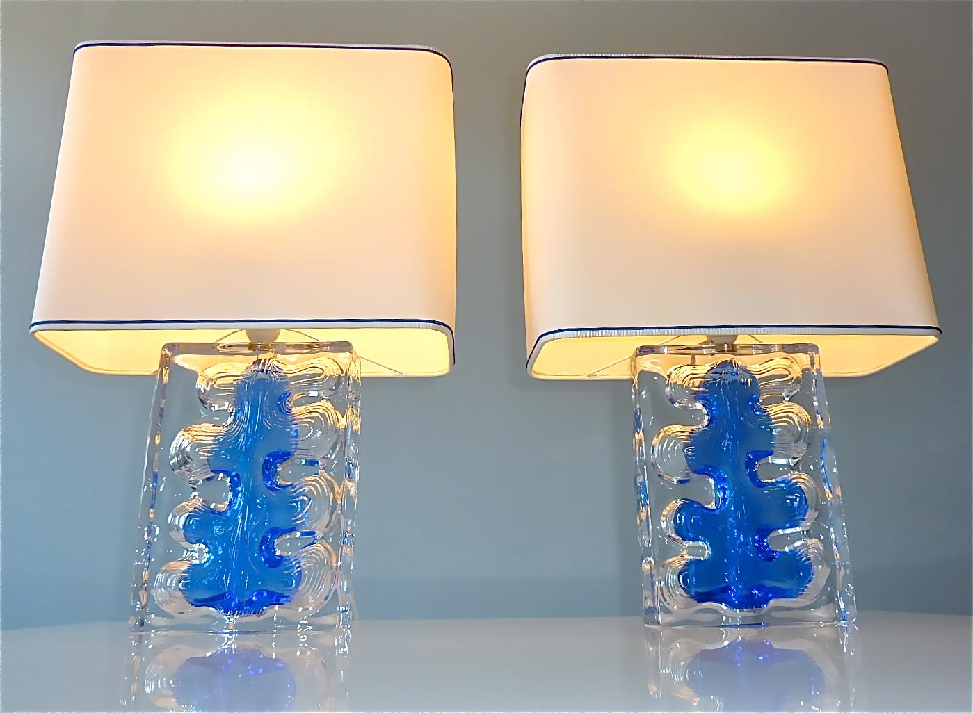 Rare pair of high quality and high end French table lamps signed Daum France around 1970s. The heavy midcentury lamp bases are made of clear crystal glass combined with ocean blue tinted glass with an abstract brutalist style decor. The lamps come