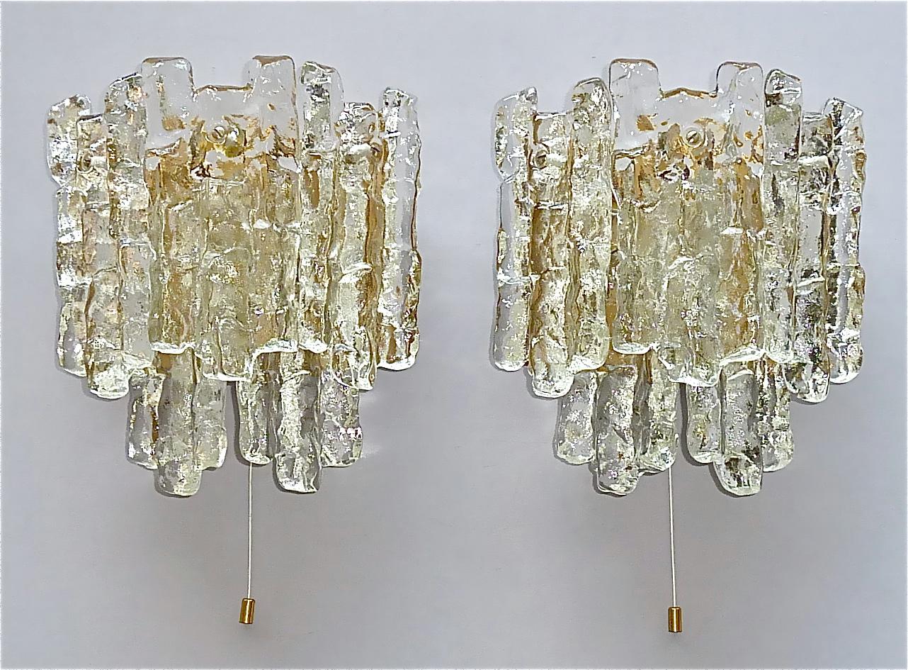 Signed large pair of textured crystal ice glass sconces or wall lights in Brutalist style by J.T. Kalmar, Austria circa 1960s. Each lamp has a golden bronze color enameled metal base with a on/off string-switch which easily can be activated and five