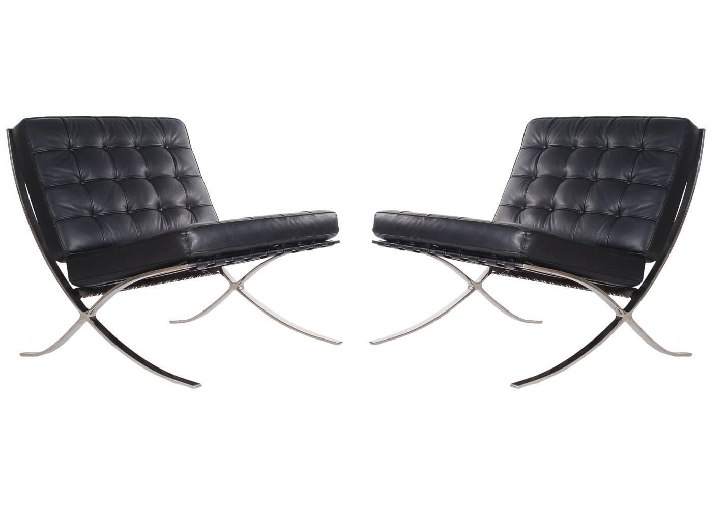 A matching authentic pair of Barcelona chairs designed by Mies van der Rohe and produced by Knoll Associates. These feature black leather cushions and the more expensive polished stainless frames rather than chrome-plated steel. Paper label and