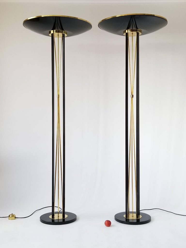 Minimalist Art Deco/ neoclassical style  Reggiani torchiere. 

In a glossy enameled black steel with solid brass rods and trim.

4 available , 2 in black as pictured and 2 white .

Well made with prime quality material.

Measure 74.5 inches high.
