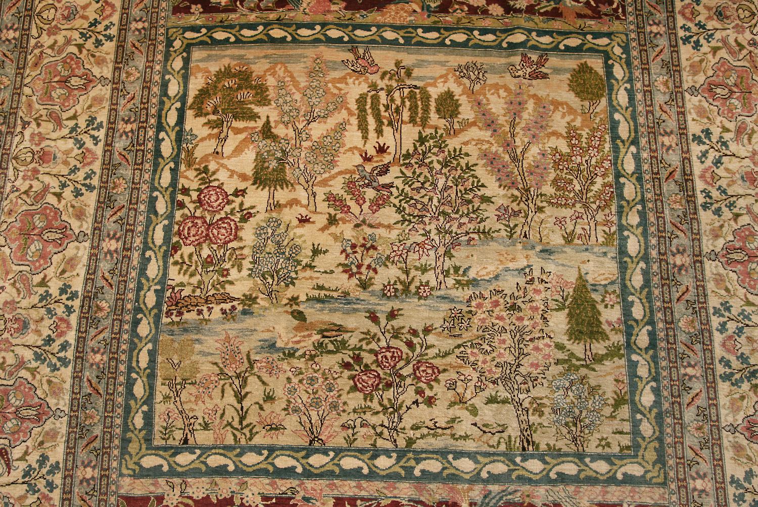 This is a modern Turkish Hereke silk metal thread rug woven in Turkey during the beginning of the 21st century circa 2000 – 2010. Its size is 167 x 122CM and the square field with various multicolored trees and landscape. Sang-de-boeuf cross panel