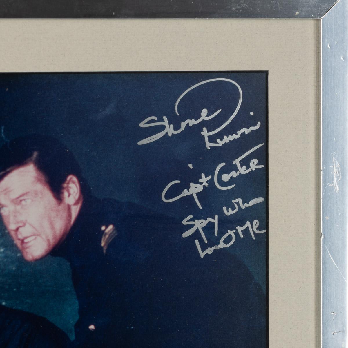 A rare signed photograph by Shane Rimmer & miniature movie poster. Shane Rimmer was a versatile actor known for his brief but memorable appearance in the James Bond film series. He played the role of Commander Carter, a U.S. Navy submarine captain,